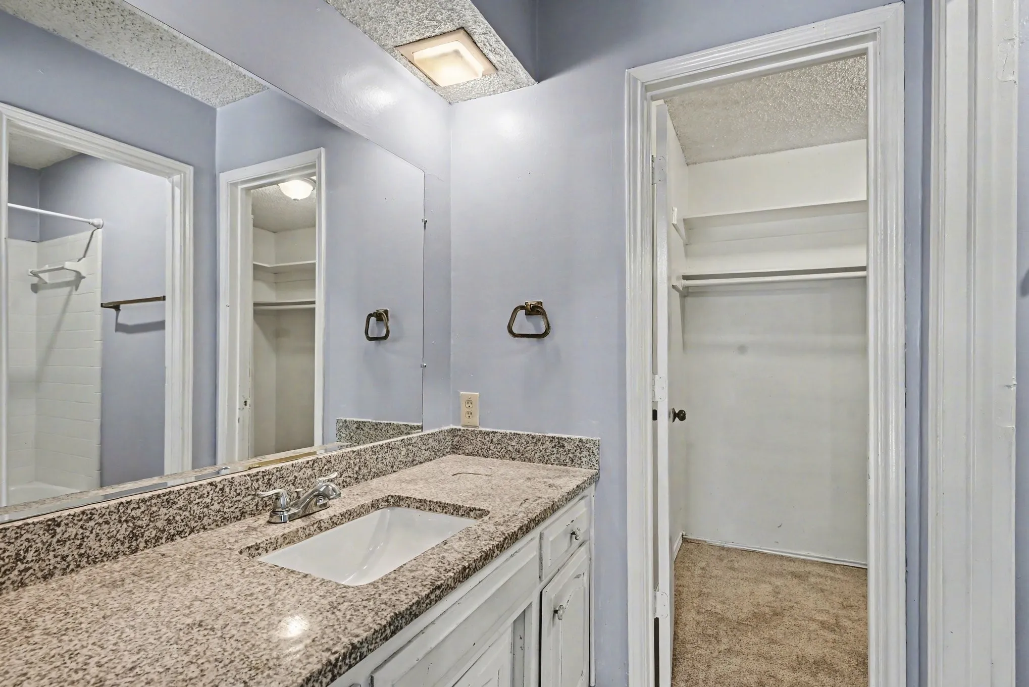 Vanity with integrated sink, speckled countertop, and chrome faucet