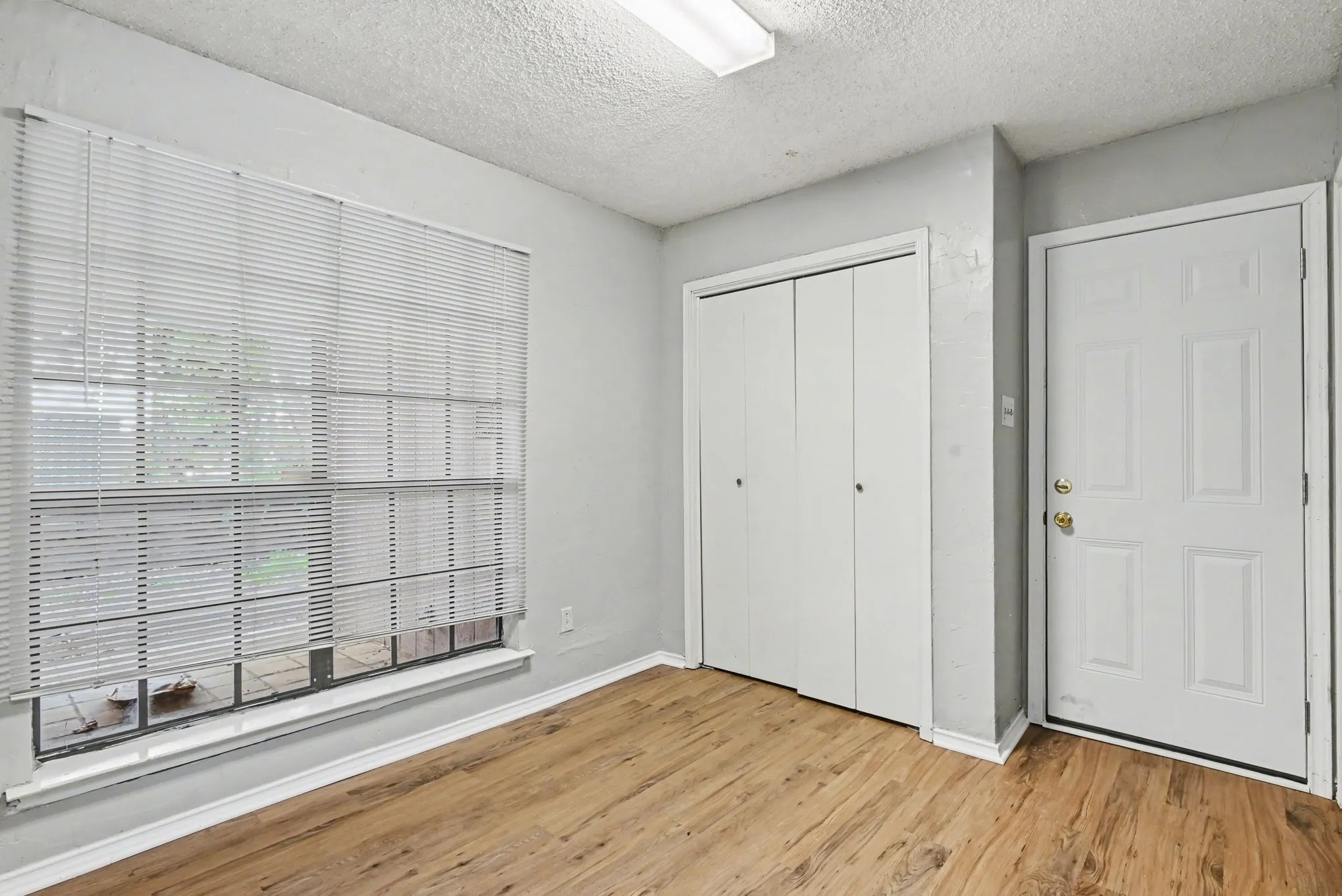 Wood-finish flooring, neutral gray wall paint, and a textured ceiling
