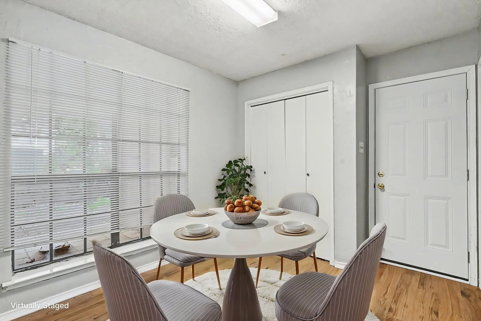 Wood-finish flooring with white walls and a large window with blinds