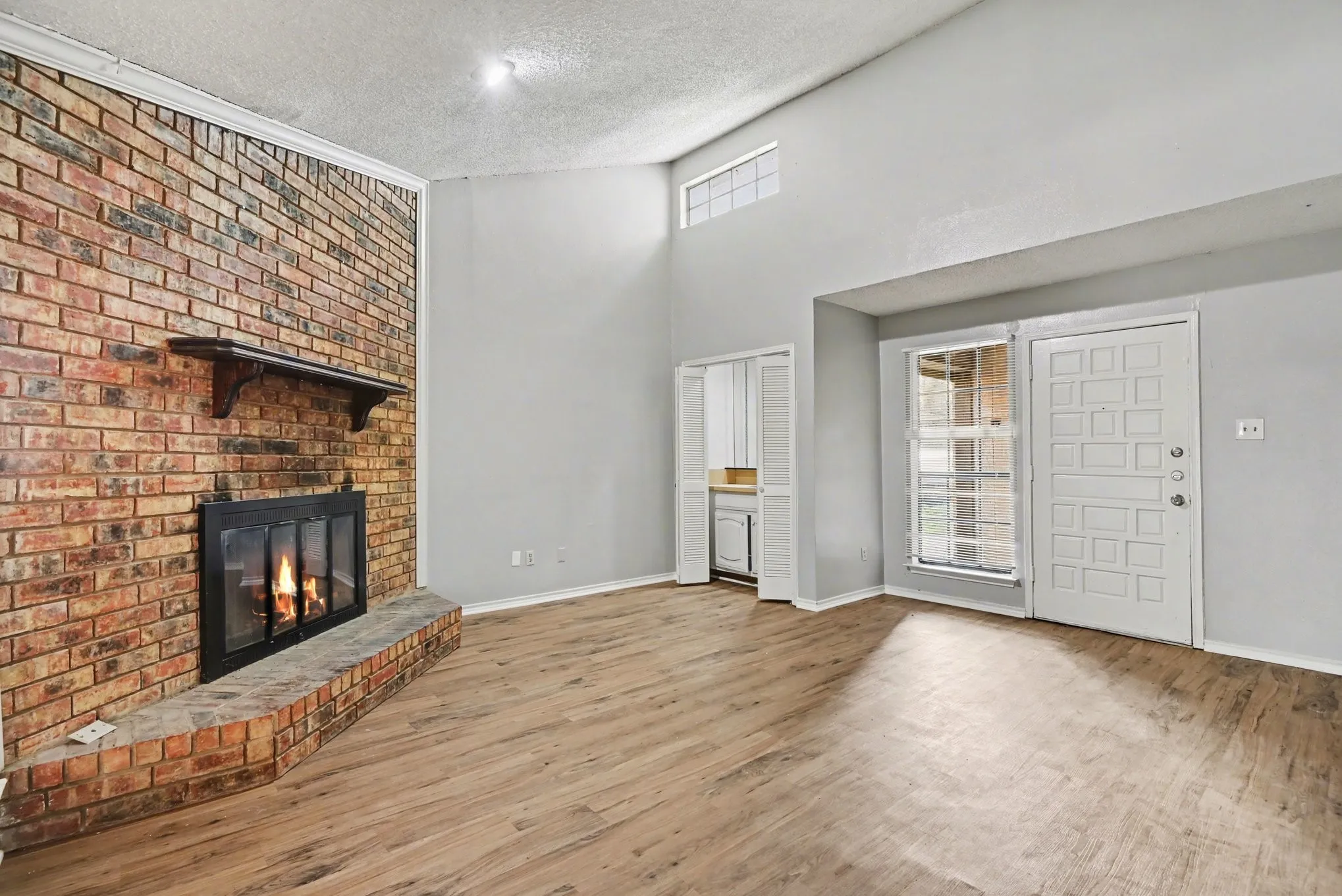 Vaulted ceilings, wood-finish flooring, brick fireplace with mantel, built-in cabinetry, and transom window