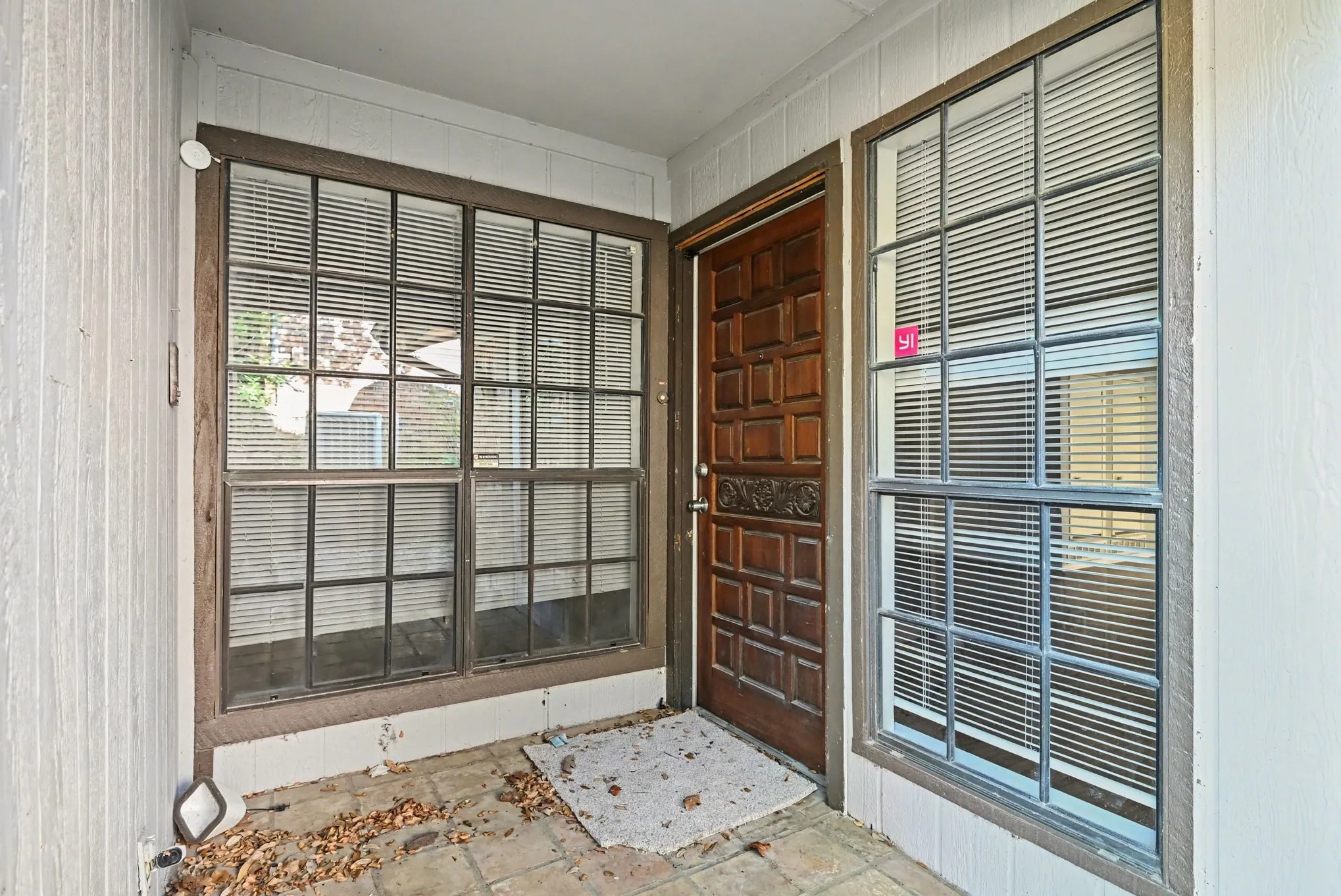 Paneled front door with decorative carving, flanked by multiple-pane windows, and a tiled entry
