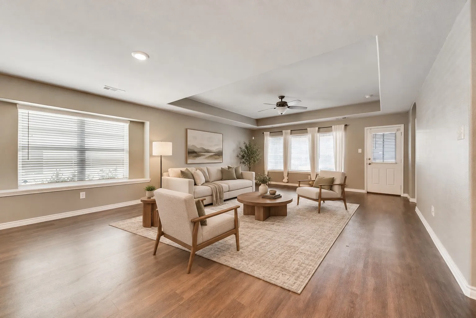Wood-finish flooring throughout, tray ceiling with a ceiling fan, multiple large windows, recessed lighting, and a paneled entry door