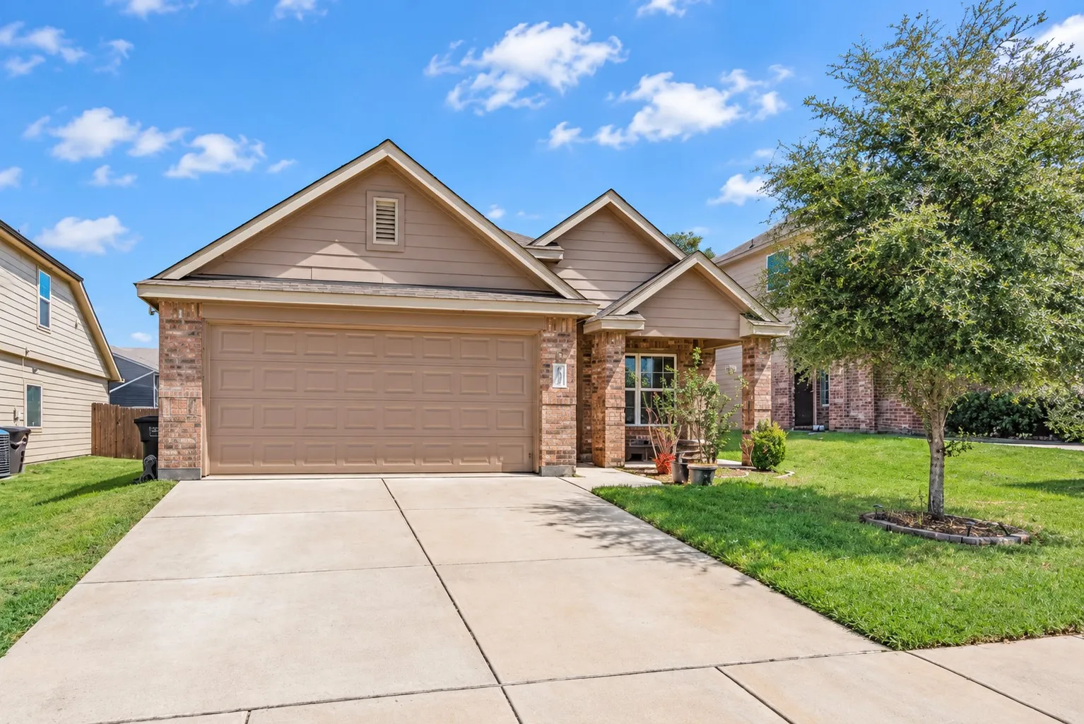 Brick and siding exterior featuring an attached garage, covered entry, and concrete driveway