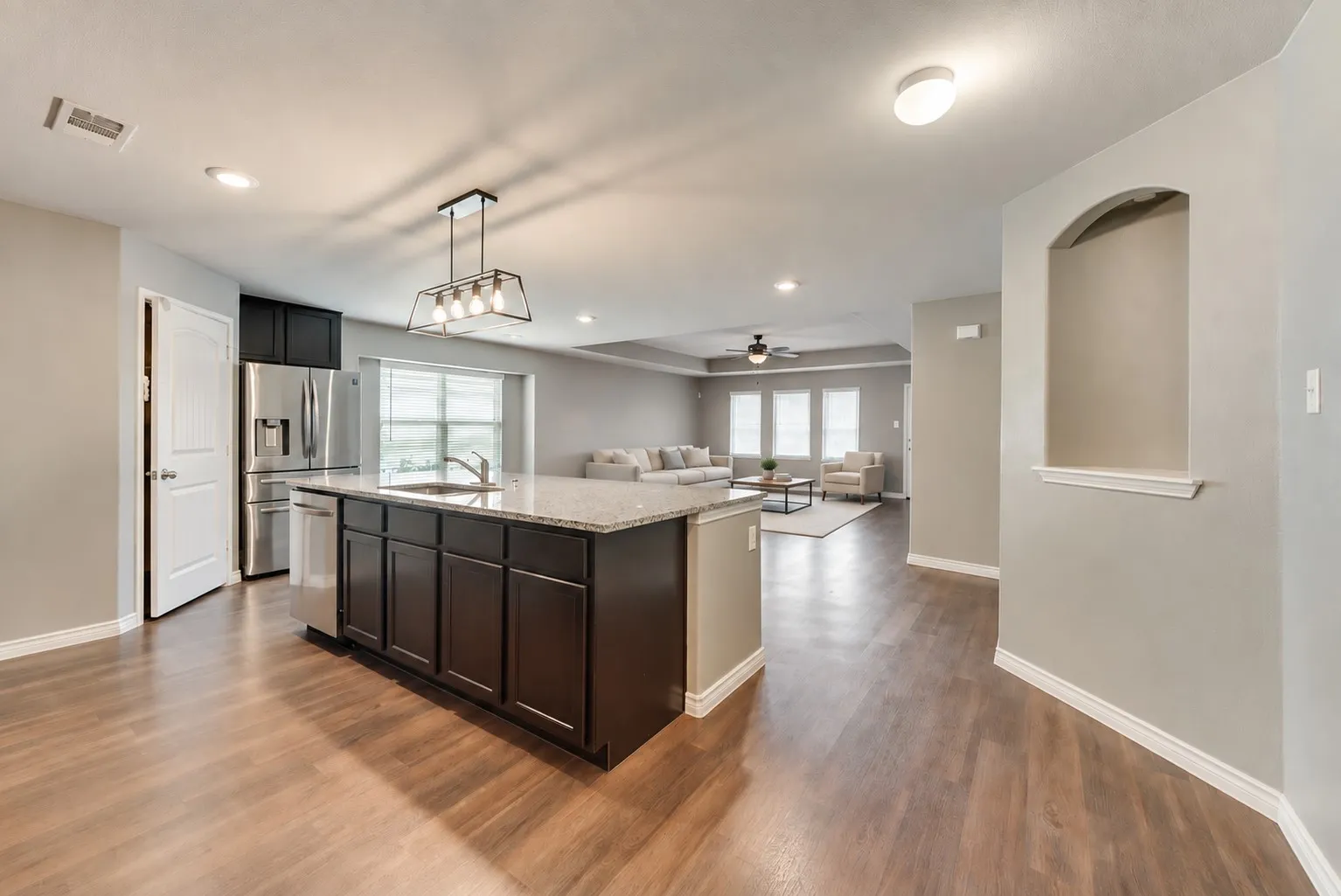 Kitchen island with granite countertop, integrated sink, and dark wood-finish cabinetry