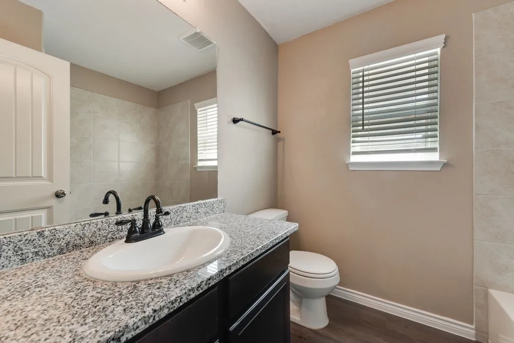 Vanity with a granite countertop, undermount sink, and dark wood-finish cabinetry