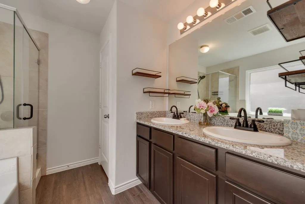 Double vanity with granite-style countertop, dark wood-finish cabinetry, and matte black fixtures