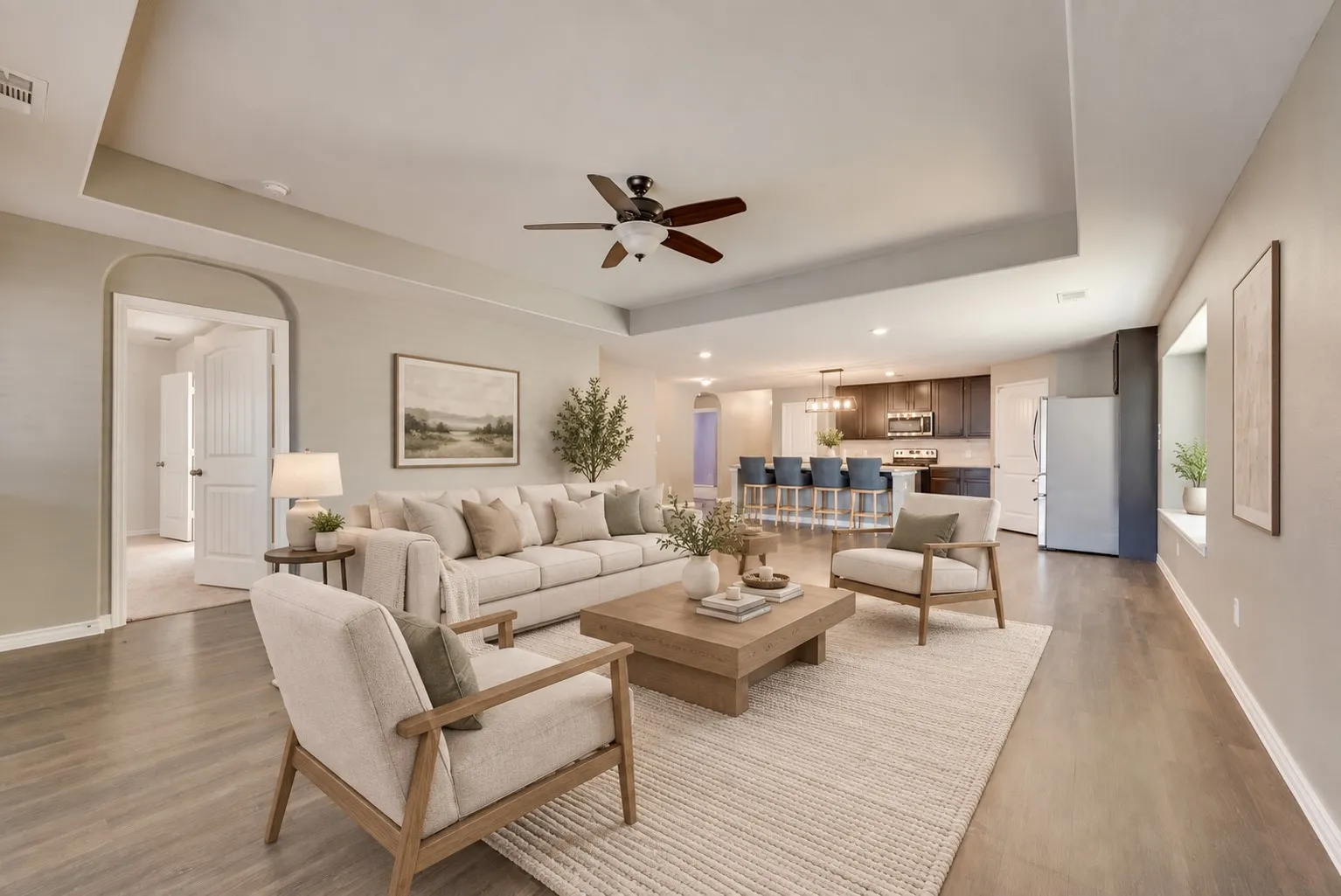 Expansive living area with wood-finish flooring, tray ceiling, and recessed lighting
