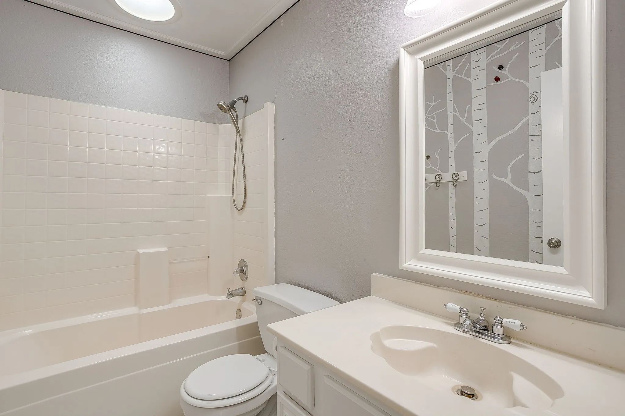 Bathroom featuring a vanity with an integrated basin, a wall-mounted framed mirror, a tub and shower combination with a handheld fixture, and recessed ceiling lighting