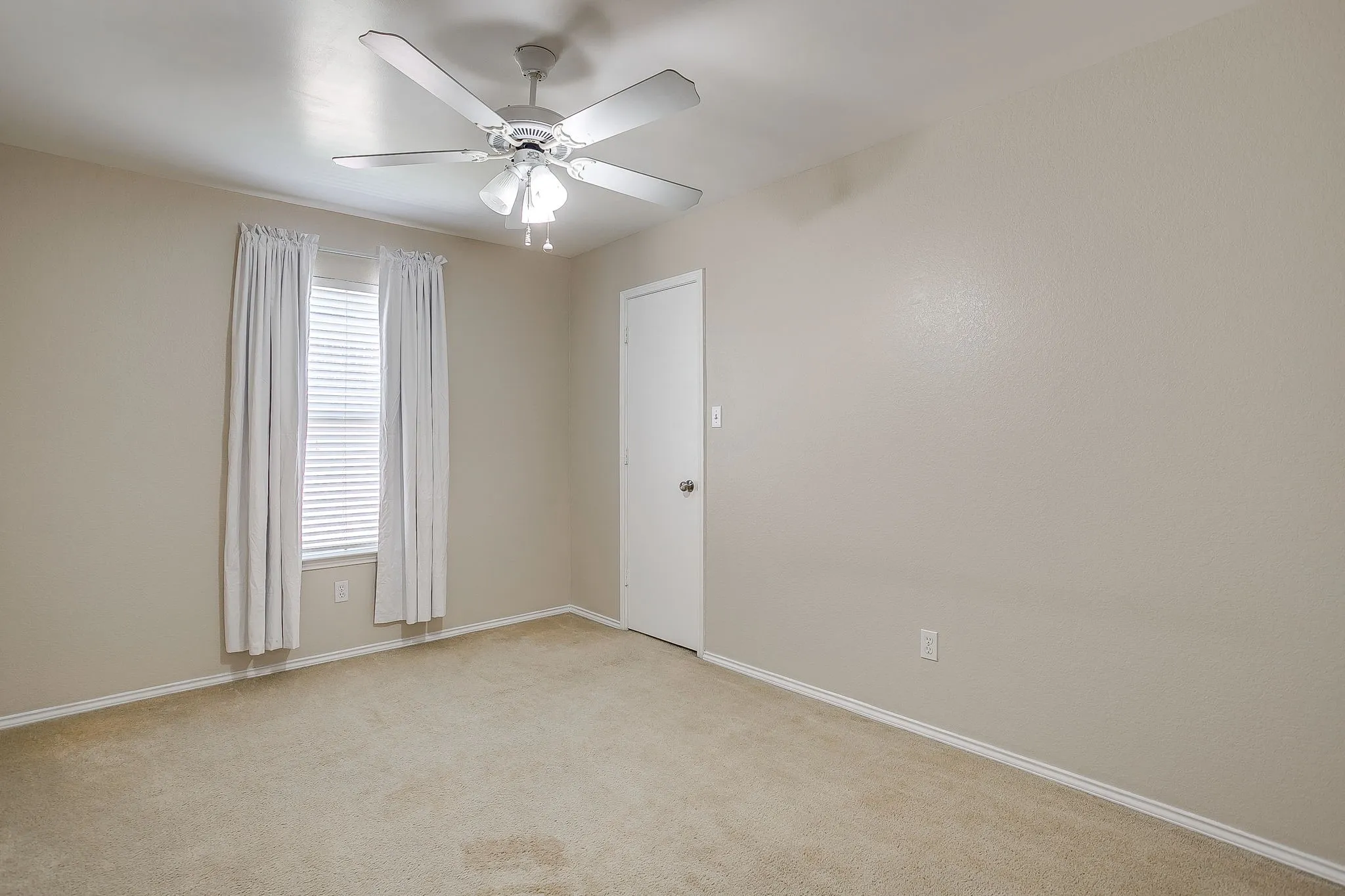 Neutral-toned walls, carpeting, ceiling fan with integrated lighting, and window blinds