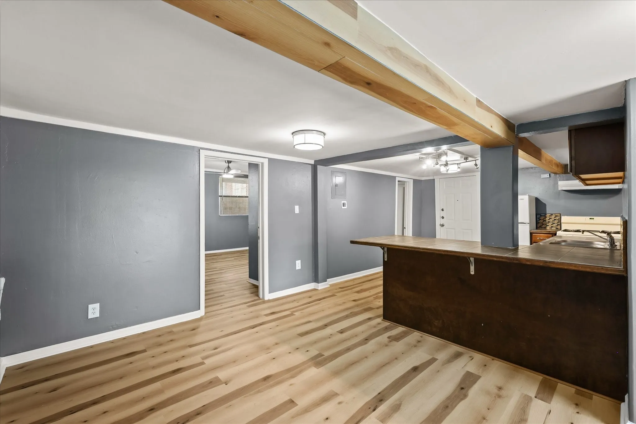Wood-finish flooring with exposed wood beams, a built-in breakfast bar, and recessed lighting
