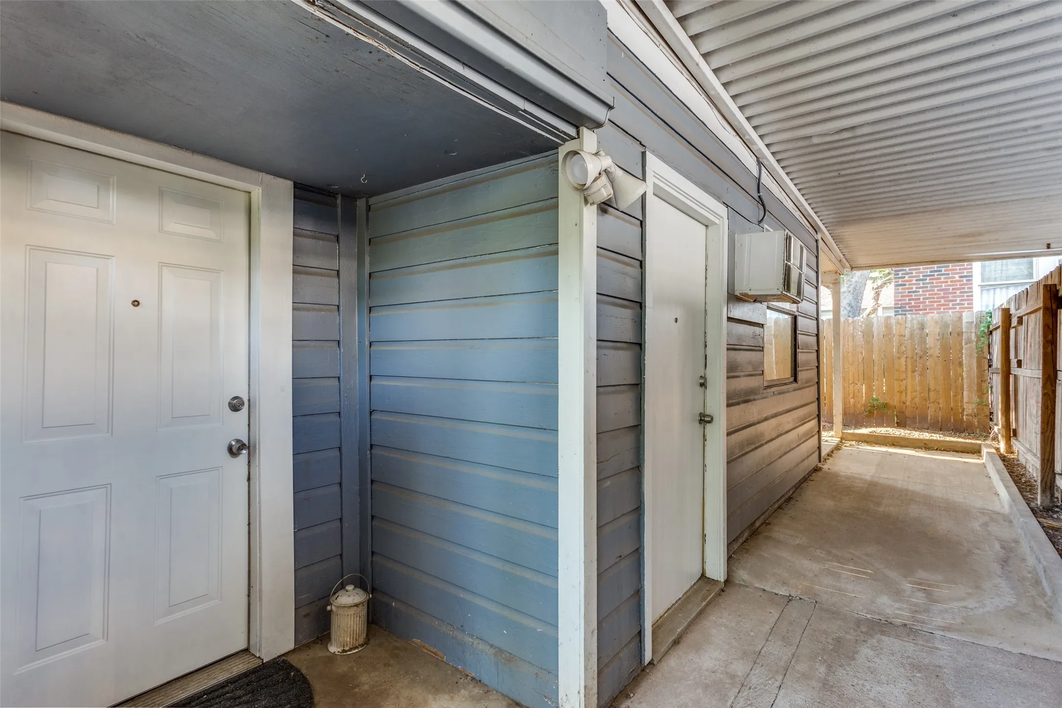 Covered entryway with two paneled doors, horizontal siding, and concrete flooring