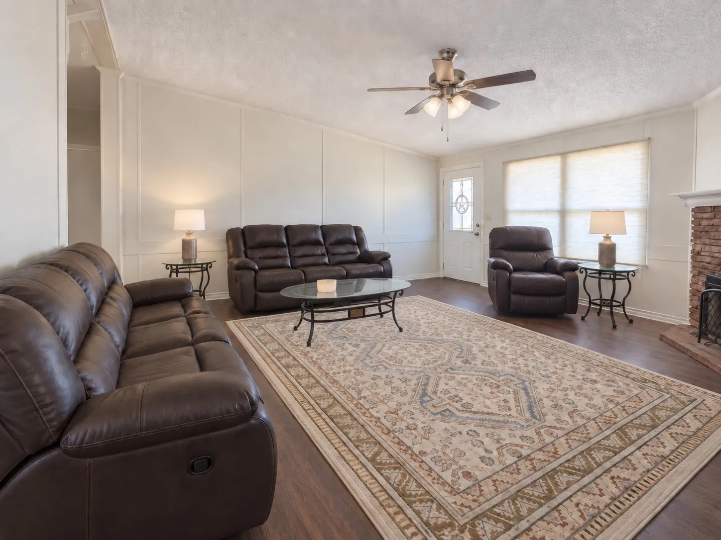 Wood-finish flooring, accent paneling, and a ceiling fan with integrated lighting