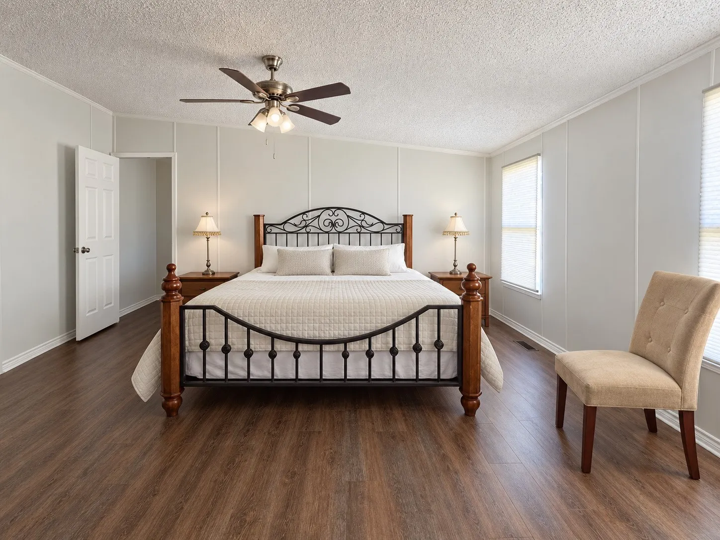 Wood-finish flooring, paneled walls, and a ceiling fan with integrated lighting