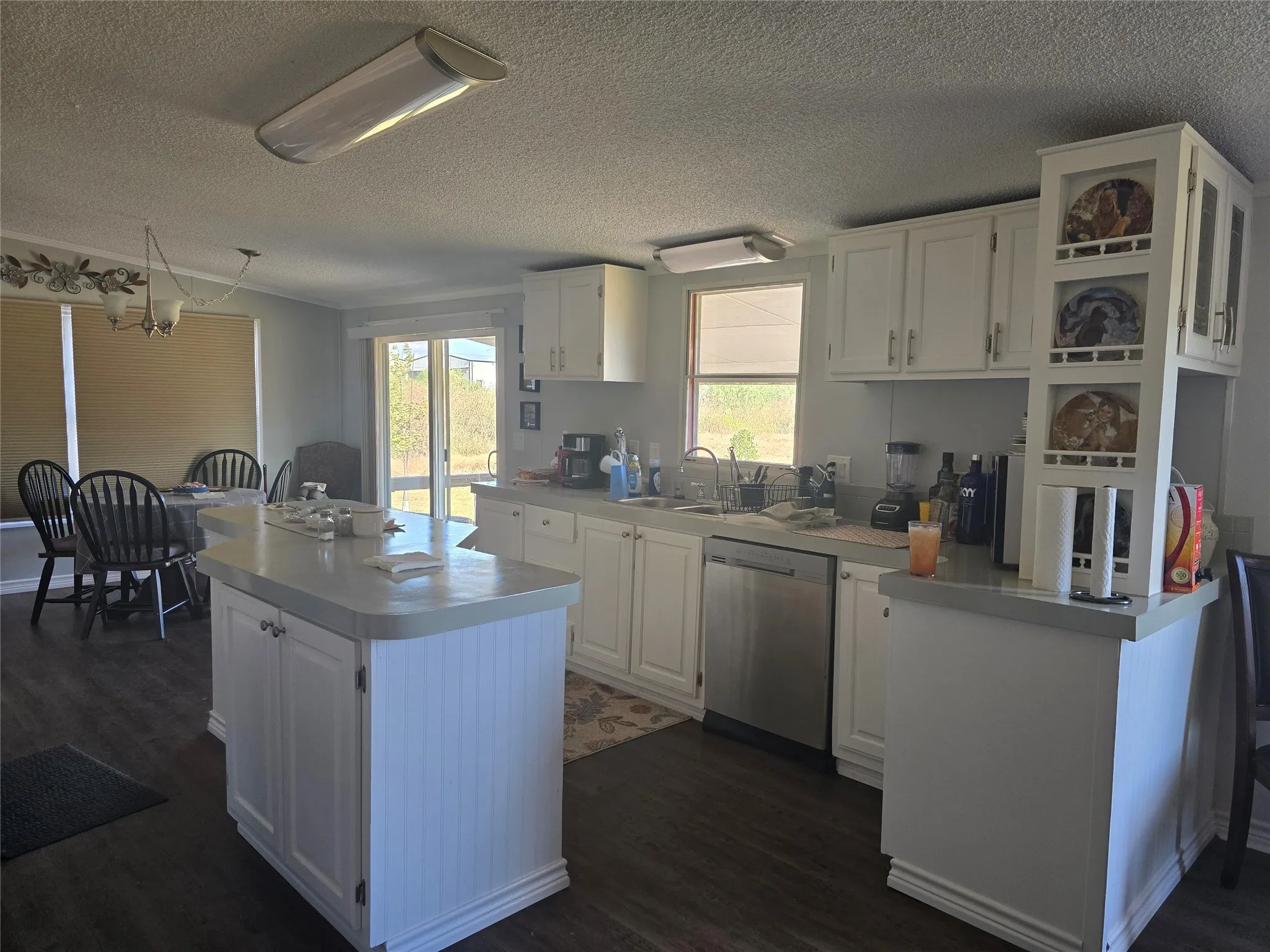 Kitchen featuring white cabinetry, a central island, stainless steel dishwasher, and wood-finish flooring