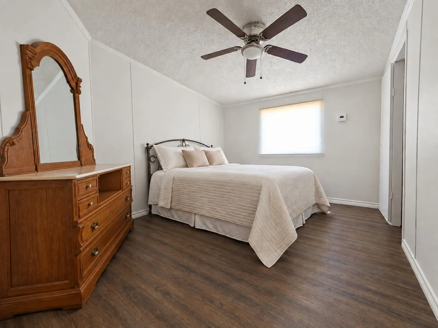 Wood-finish flooring, ceiling fan, and white walls