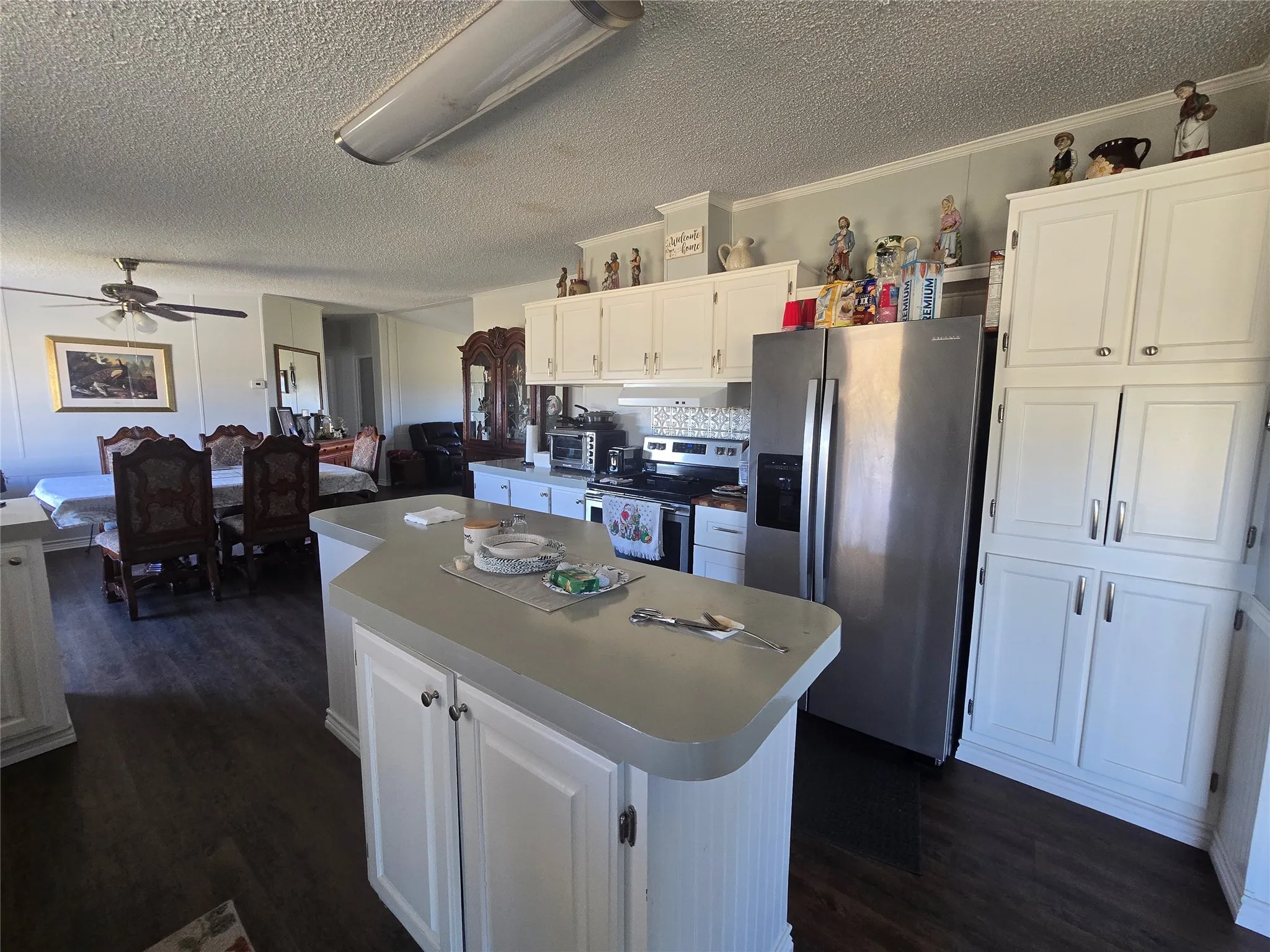 Kitchen featuring white cabinetry, a central island with a light-toned countertop, and stainless steel appliances