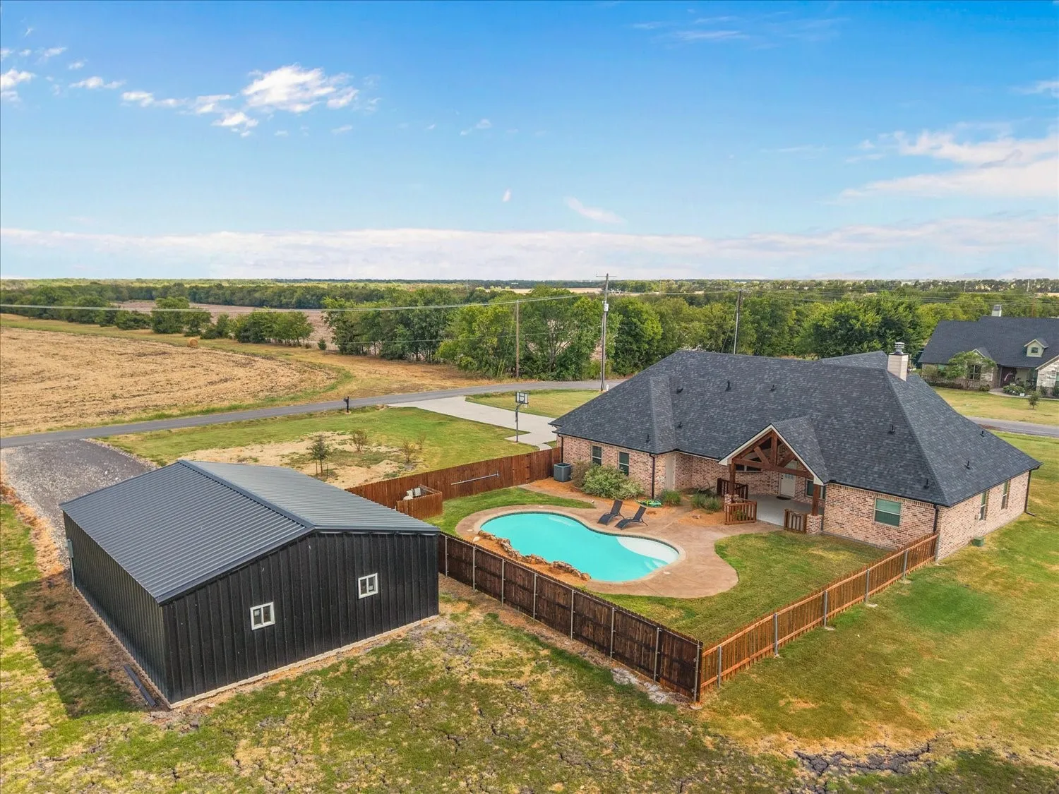 Brick exterior residence featuring a gabled roof, an inground swimming pool, and an outdoor patio space