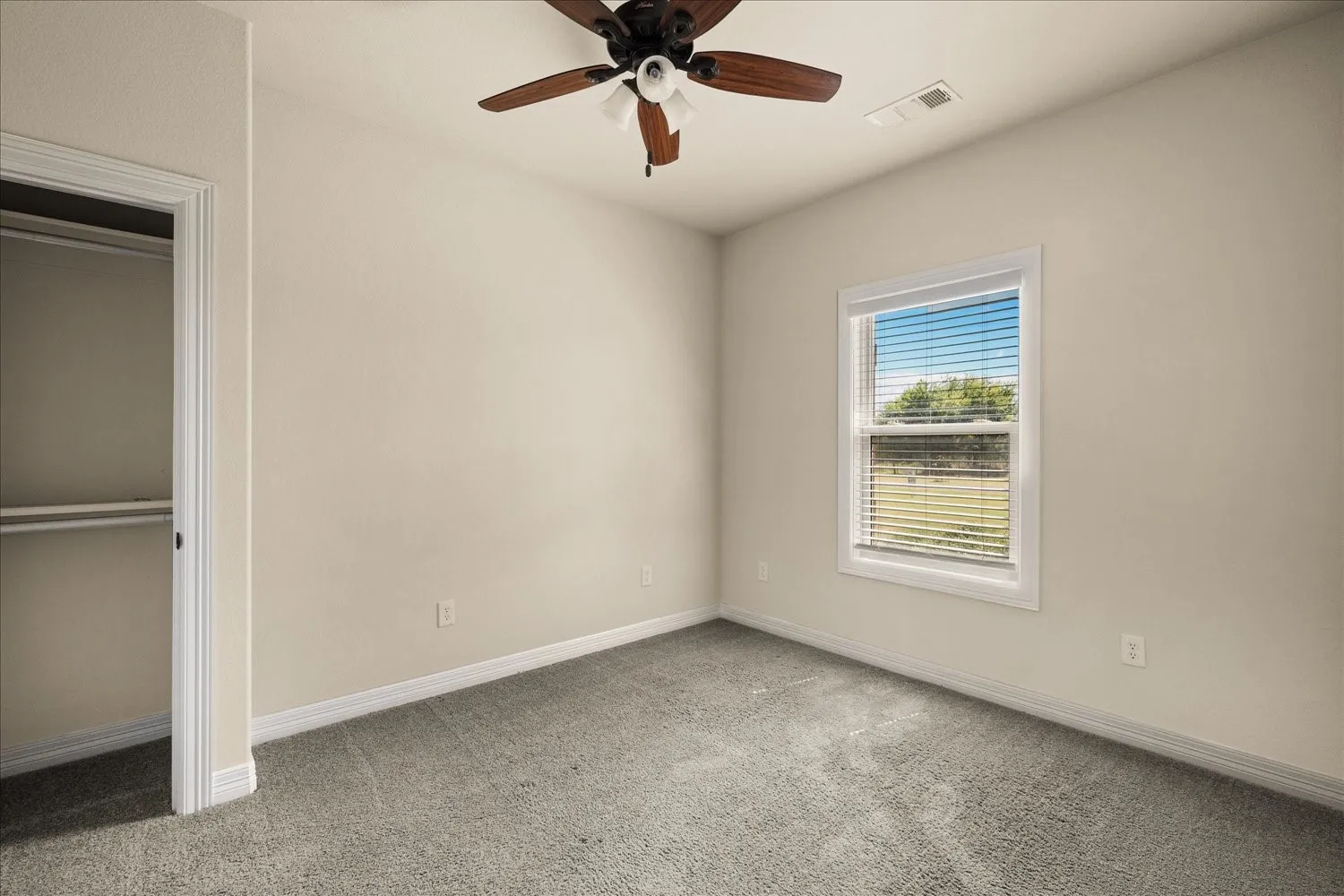 Recessed closet with a built-in shelf and hanging rod, carpeted flooring, and a ceiling fan with light fixture