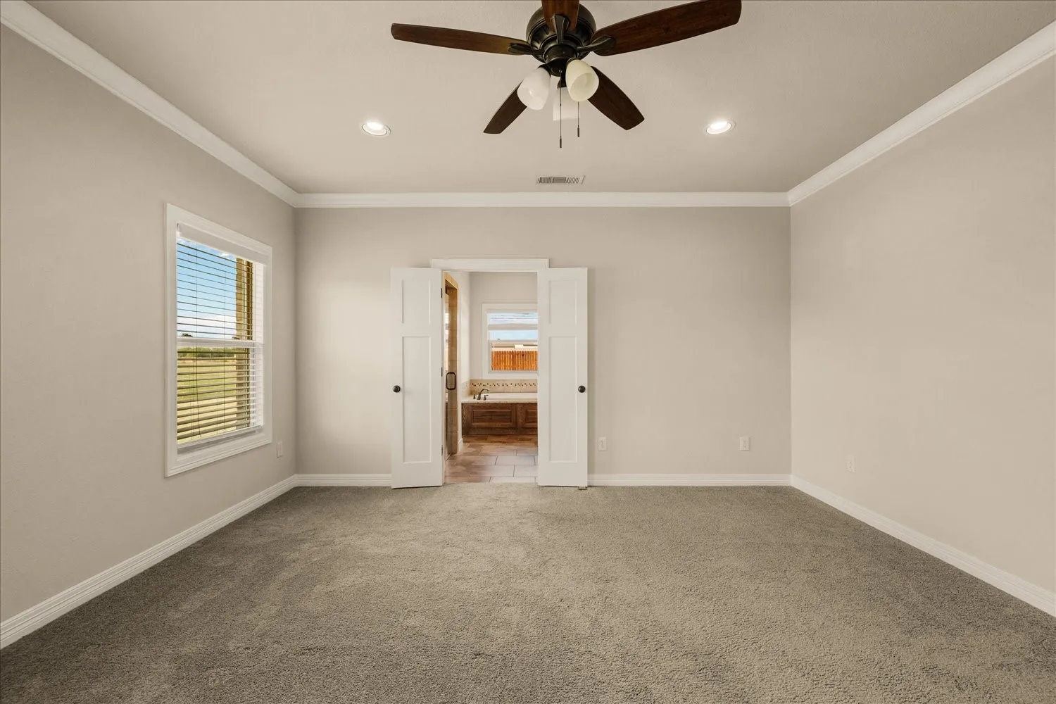 Spacious room featuring neutral carpeting, a ceiling fan, recessed lighting, and crown molding