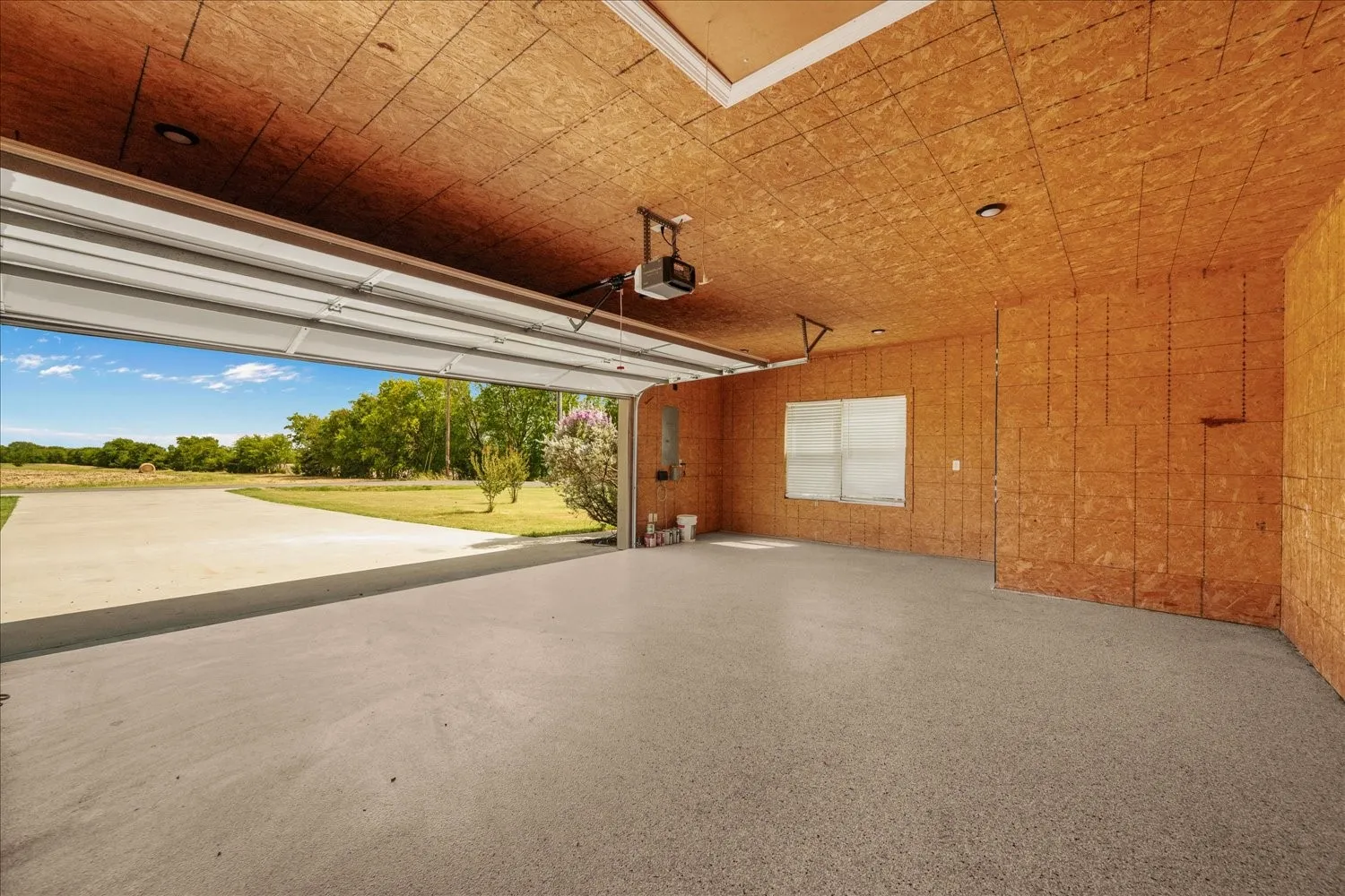 Spacious garage featuring a durable concrete floor, overhead door, and a single window