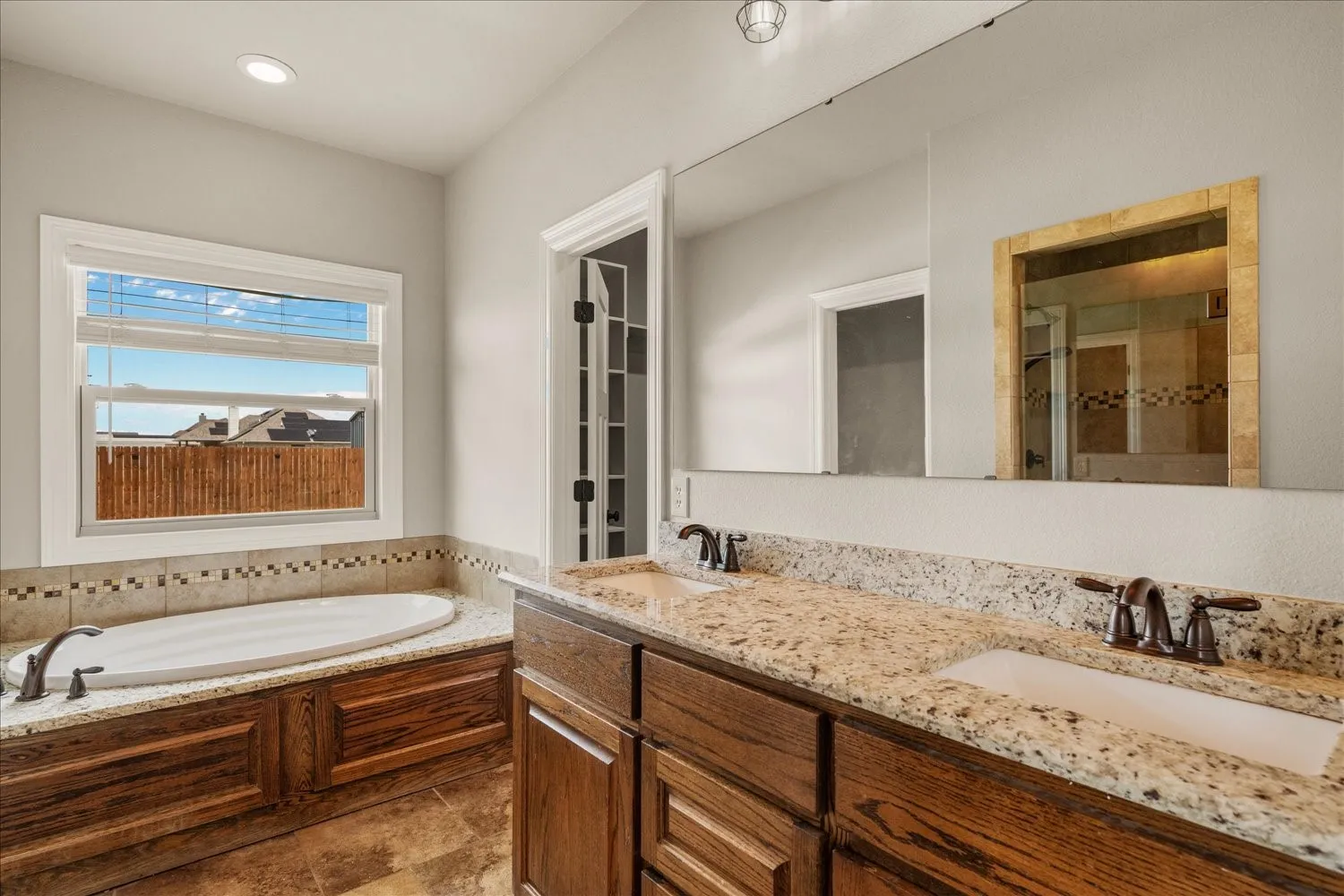 Dual vanity with granite-style countertops, wood-finish cabinetry, and undermount sinks