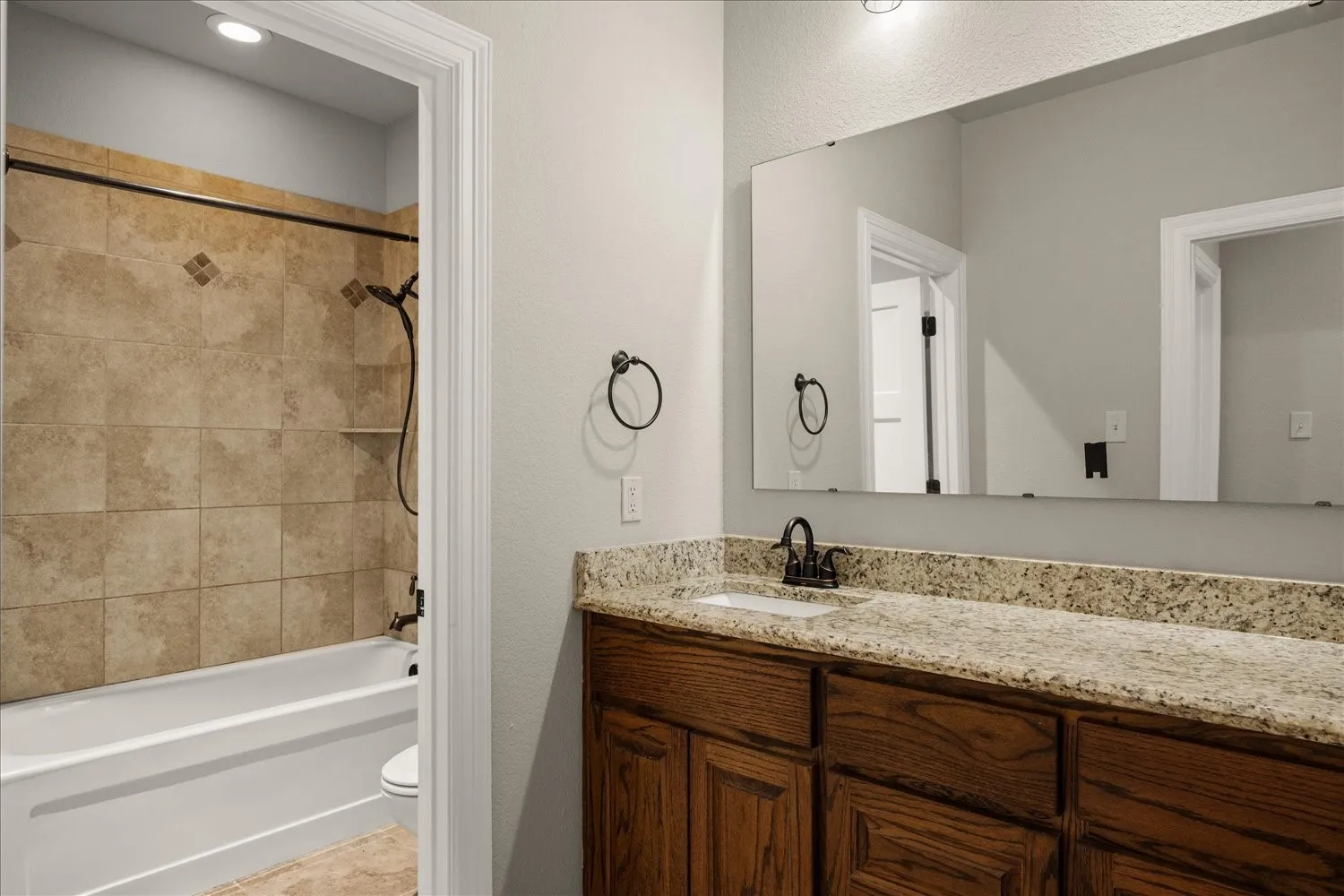 Vanity with a granite countertop and wood-finish cabinetry