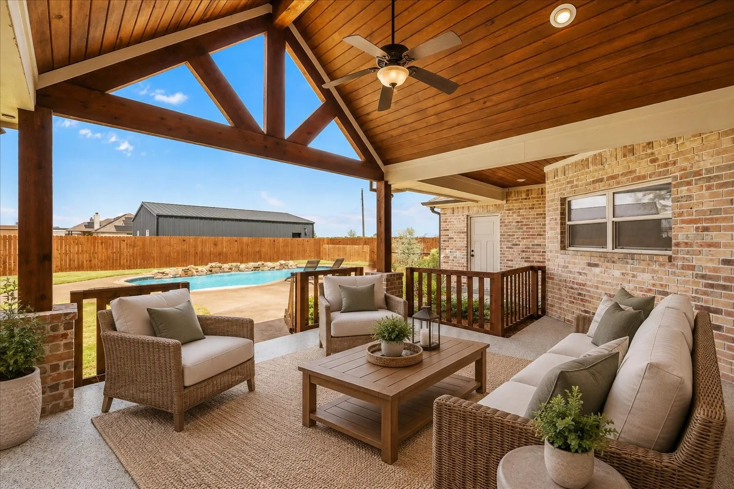 Covered patio featuring an exposed wood beam ceiling, ceiling fan, and brick exterior