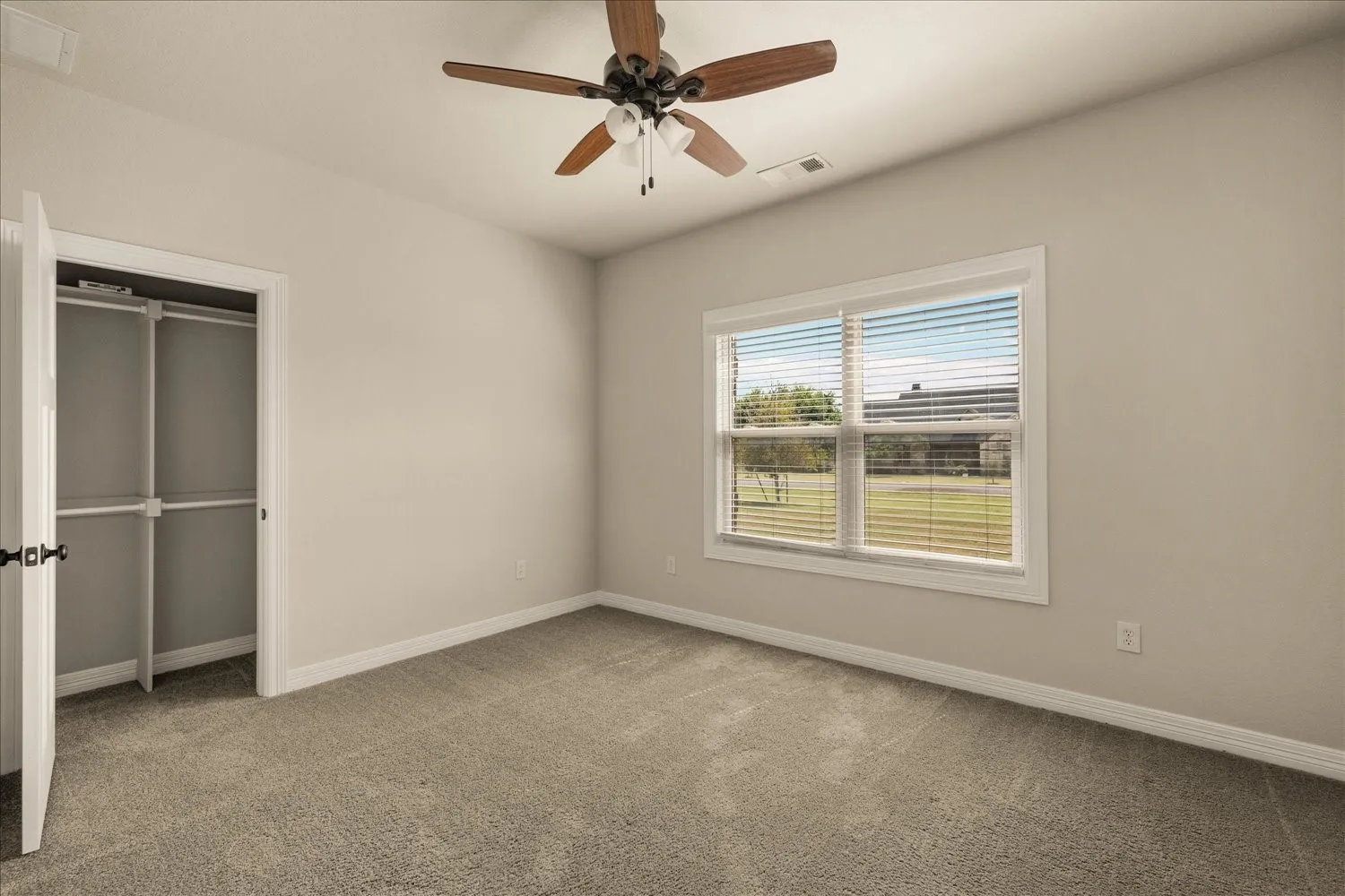 Neutral-toned walls with carpeted flooring, featuring a ceiling fan with integrated lighting