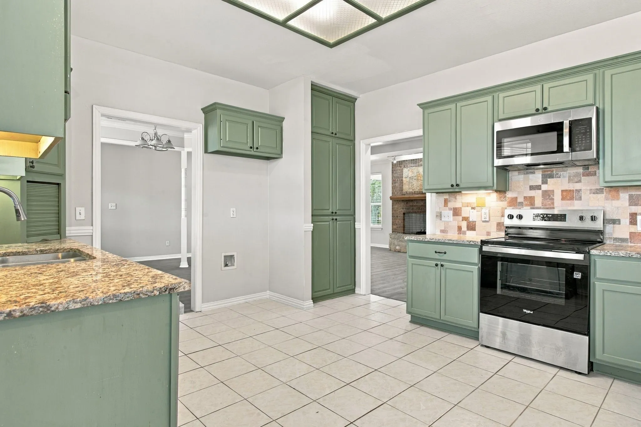 Green cabinetry with stone-finish countertops, stainless steel appliances, and a tiled backsplash