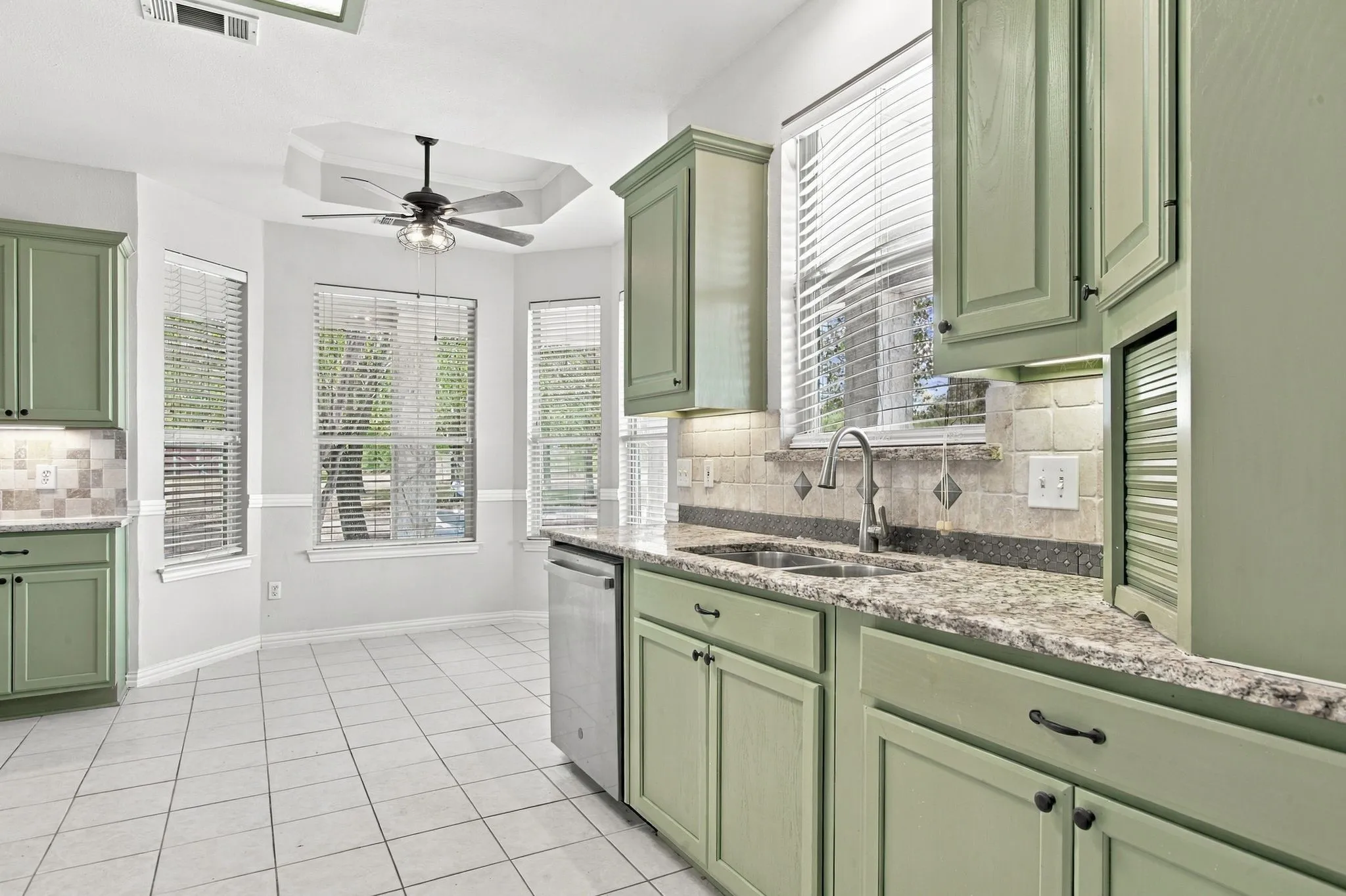 Kitchen featuring light green cabinetry, tile flooring, and a decorative tile backsplash