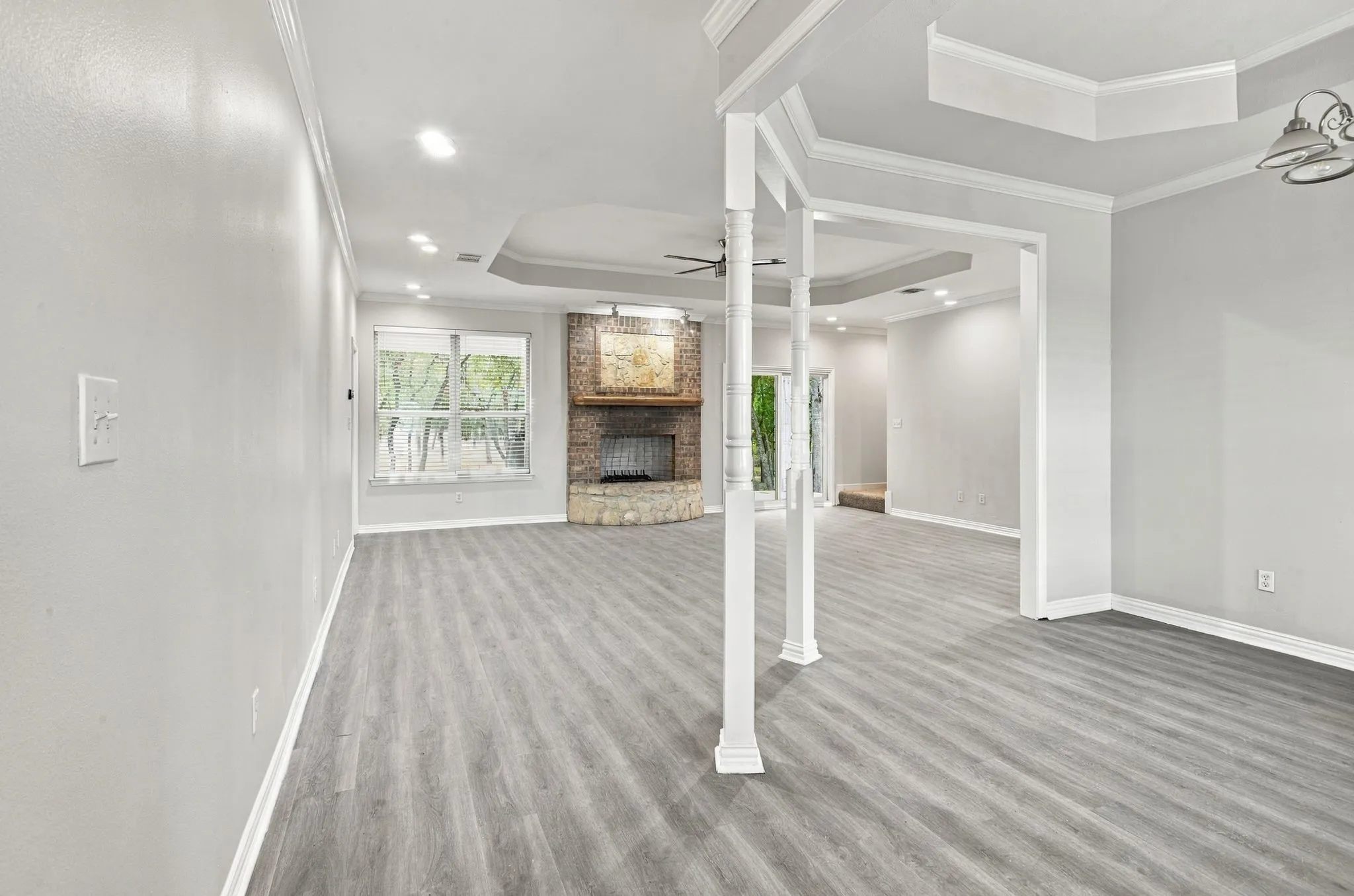 Spacious interior featuring wood-finish flooring, a brick and stone fireplace, recessed lighting, and tray ceilings