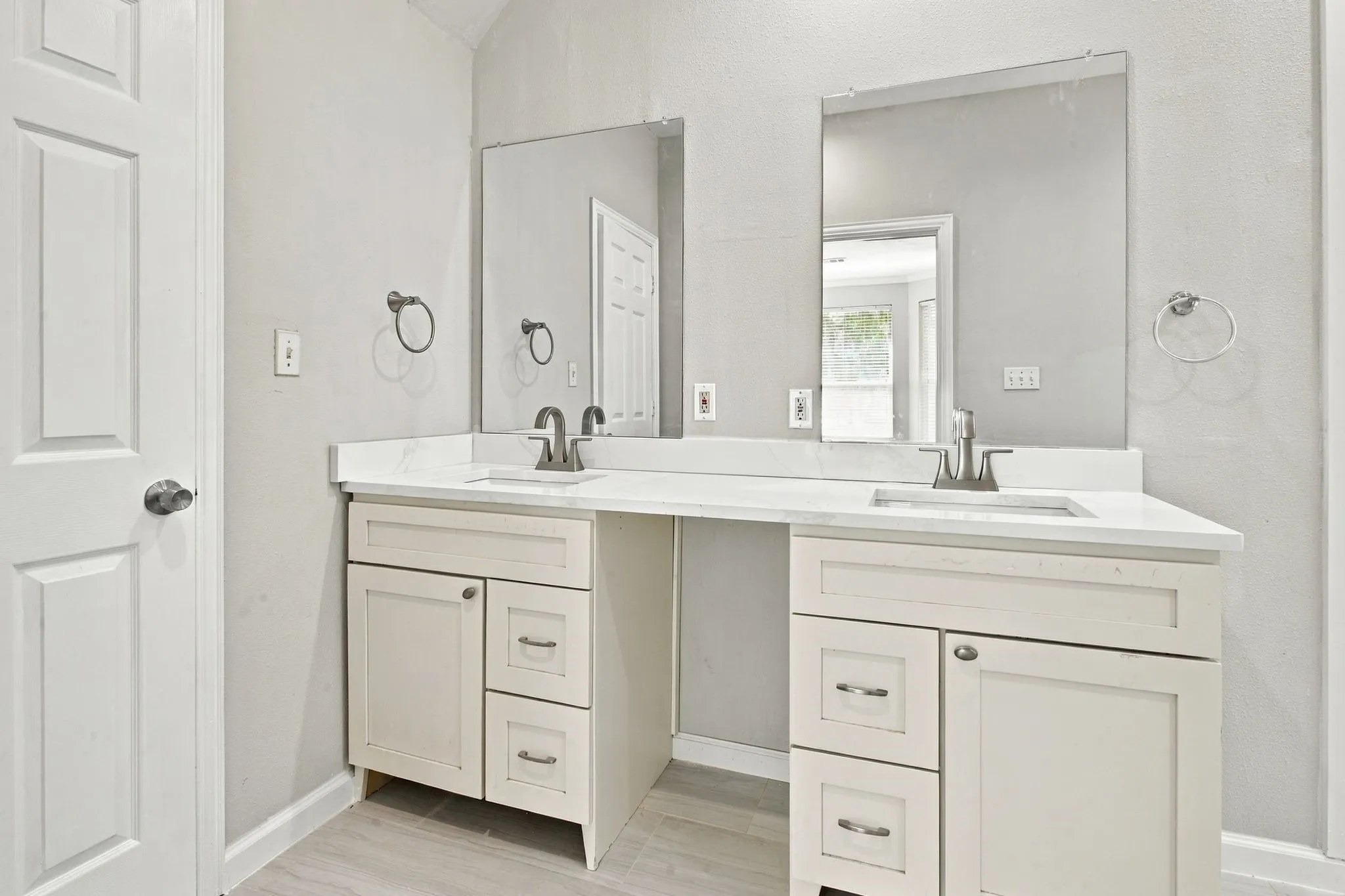 Dual vanity with white cabinetry, solid surface countertops, undermount sinks, and brushed nickel fixtures