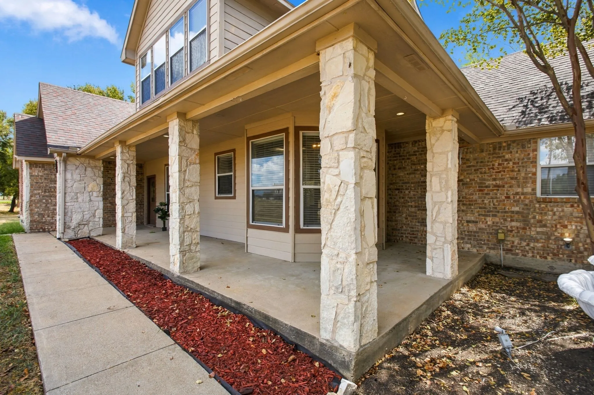Covered porch with stone-clad columns and a concrete walkway