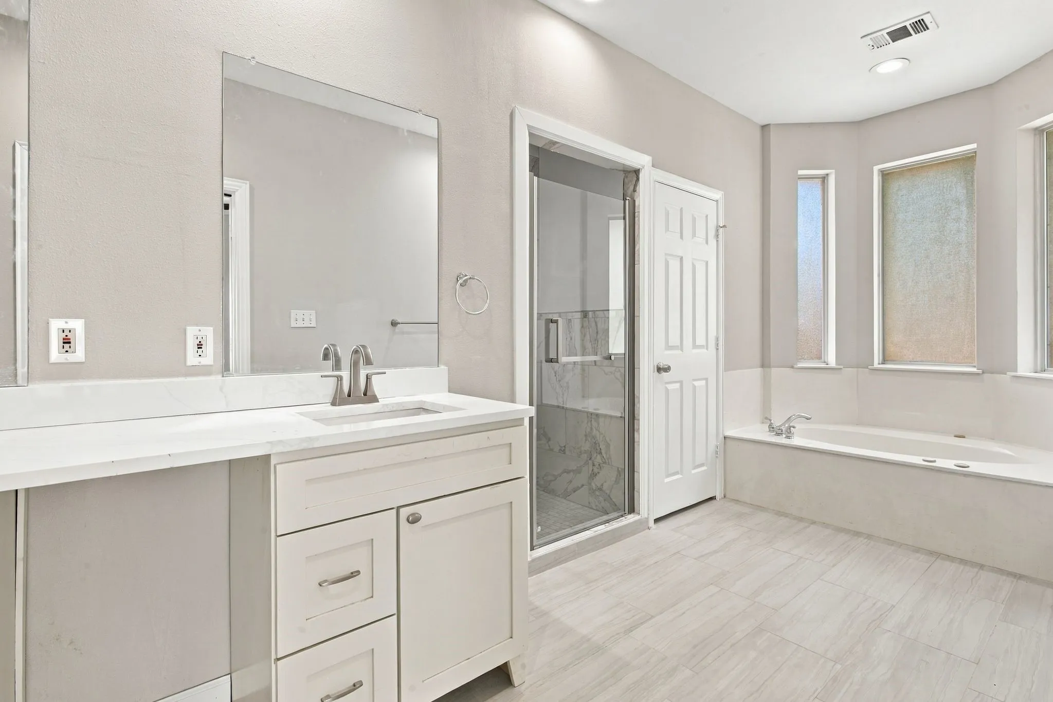 Dual vanity with stone countertop and integrated sink, walk-in shower with clear glass enclosure and tiled walls, built-in bathtub, and tiled flooring