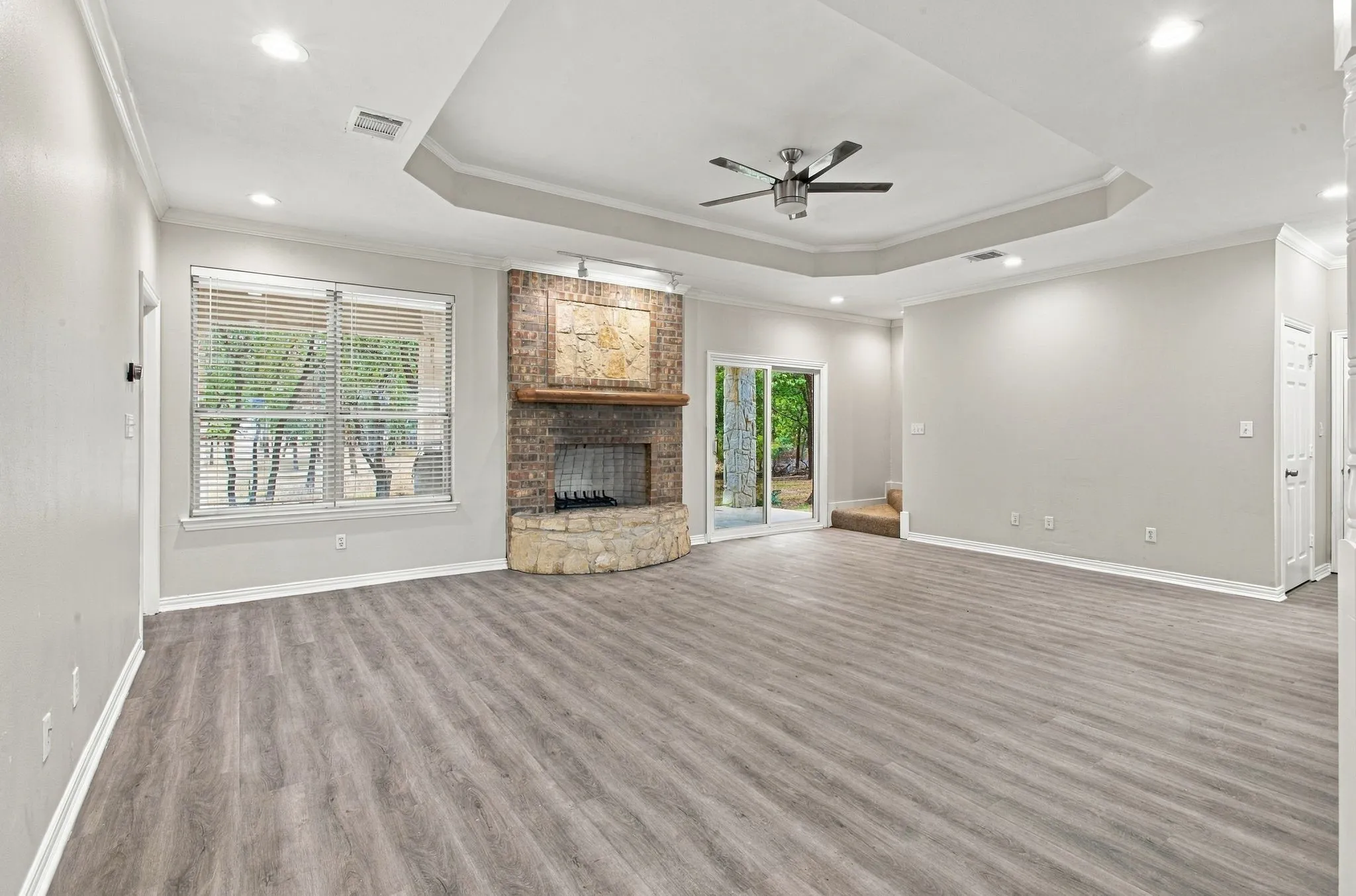 Spacious room featuring wood-finish flooring, a tray ceiling with a ceiling fan, and recessed lighting