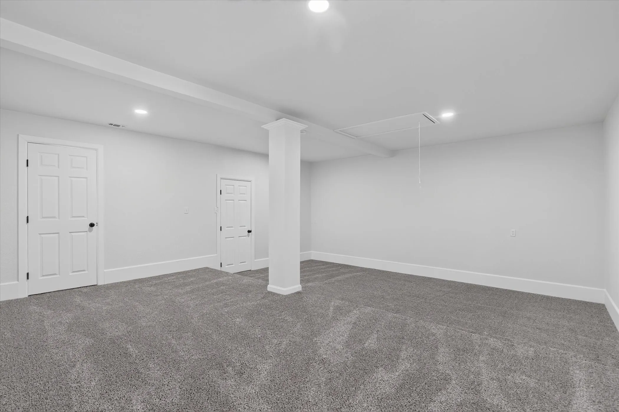 Spacious room featuring neutral carpeting, recessed lighting, and white paneled doors
