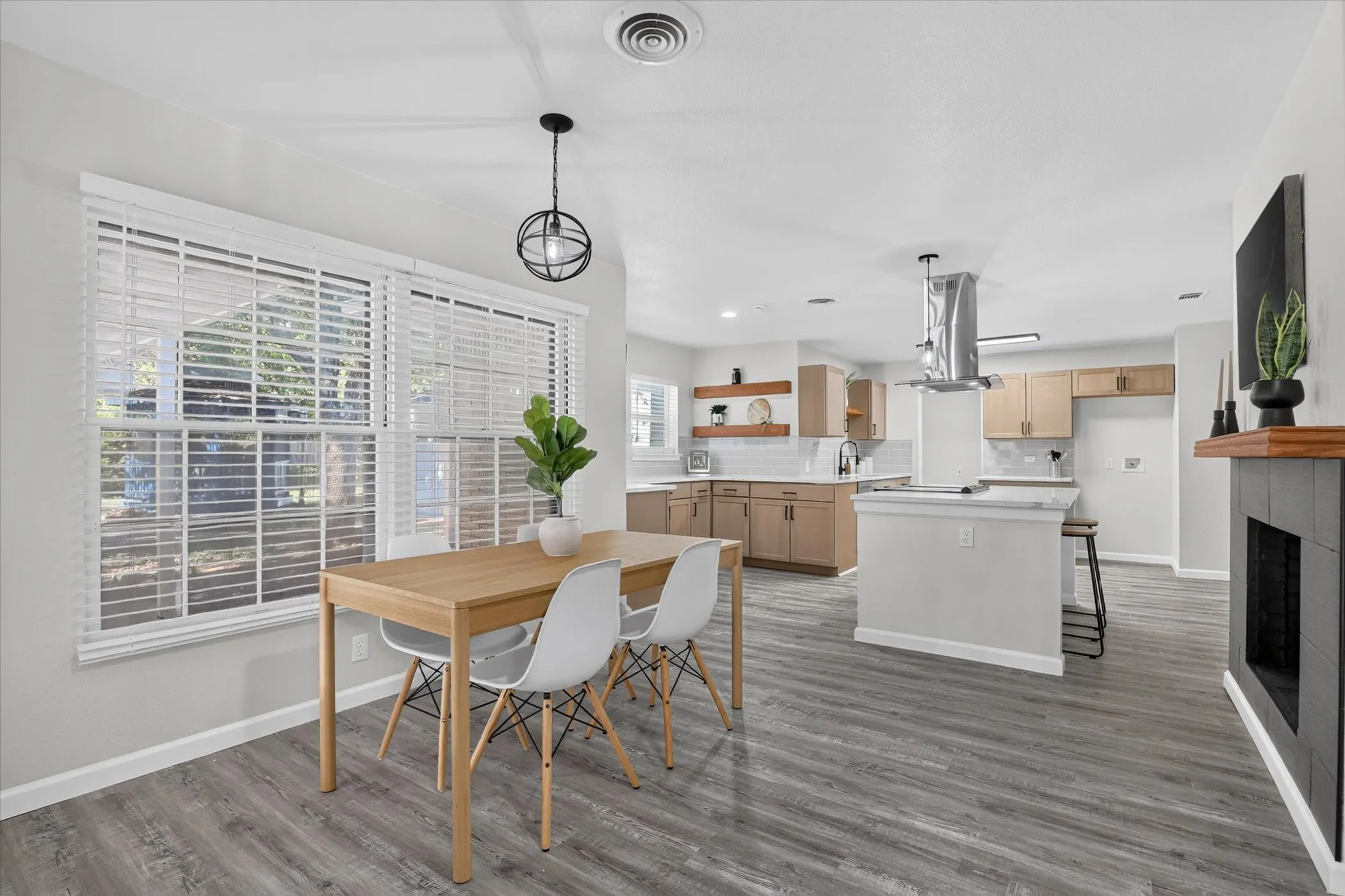 Spacious interior featuring wood-finish flooring, a contemporary fireplace, and a kitchen with light wood-tone cabinetry