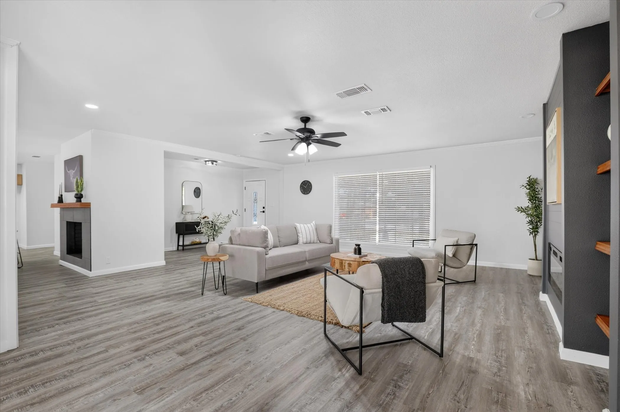 Spacious living area featuring wood-finish flooring, a ceiling fan, and a built-in fireplace with a wood mantle