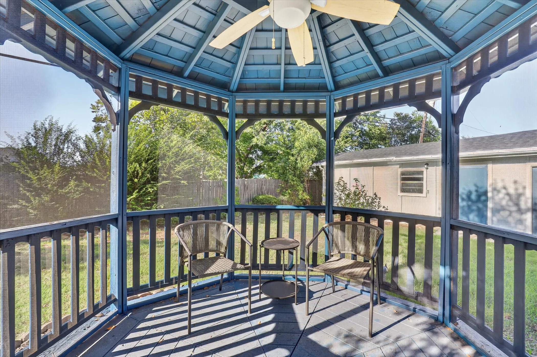 Screened gazebo featuring a ceiling fan, wood flooring, and slatted railing