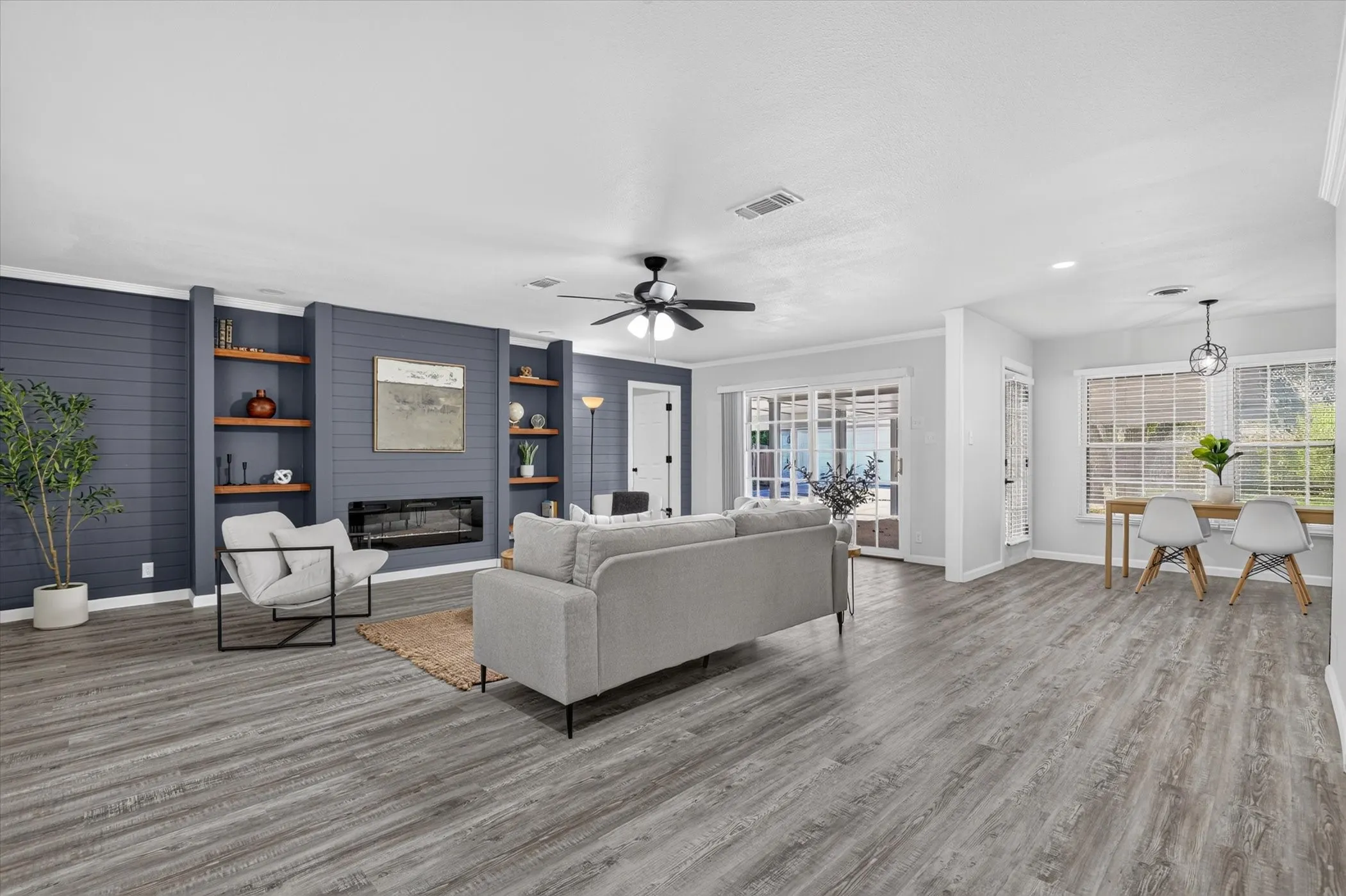 Wood-finish flooring throughout, living space with built-in shelving, electric fireplace, and ceiling fan