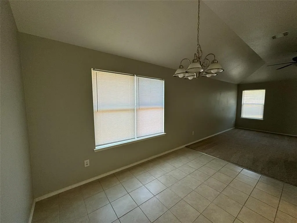 Vaulted ceilings, tile flooring, window treatments, and an overhead light fixture