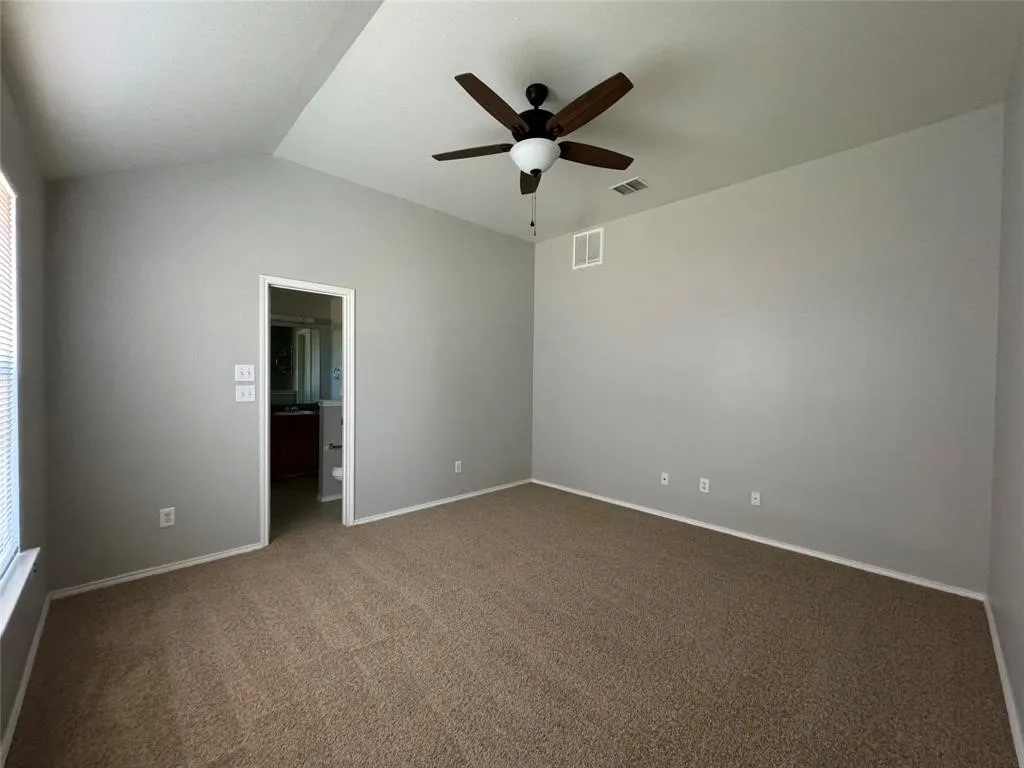 Neutral wall paint, vaulted ceiling, ceiling fan, carpeted flooring, and window with blinds