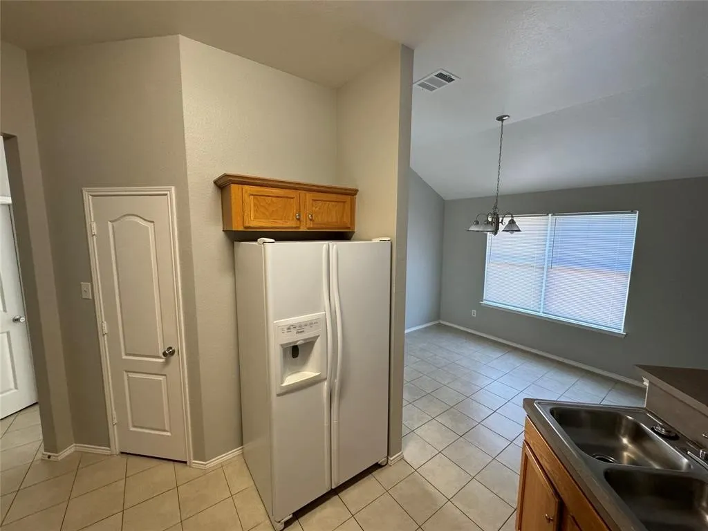 Kitchen area featuring tile flooring, wood cabinetry, and a double basin stainless steel sink