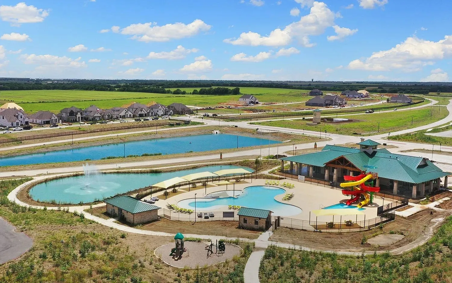 Community amenity center featuring a resort-style pool with waterslides, a separate children's play area, and a large clubhouse building