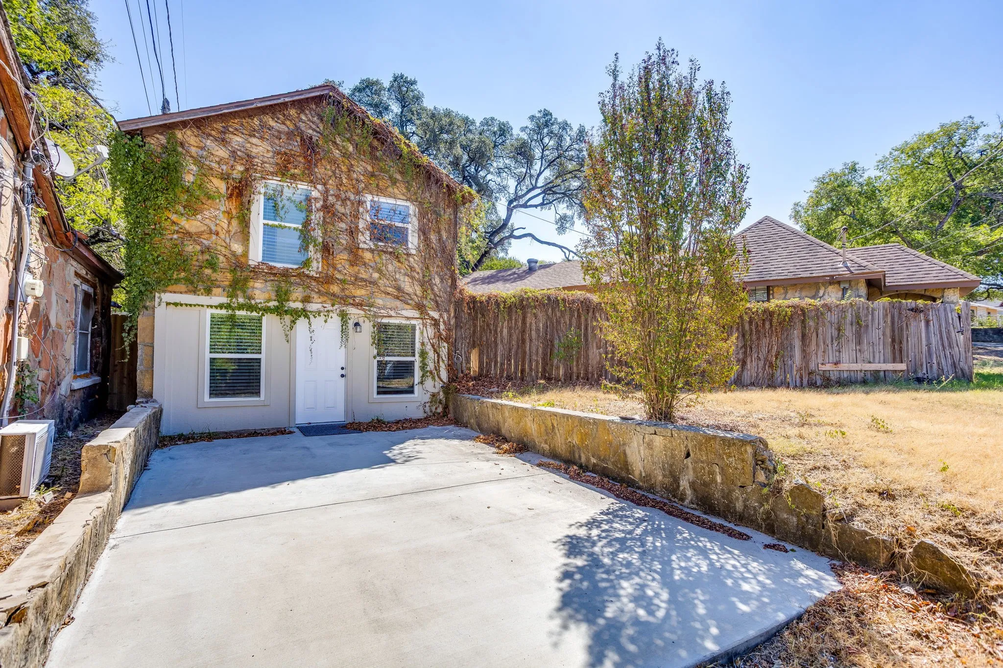 Two-story exterior with natural vine coverage and a white entry door