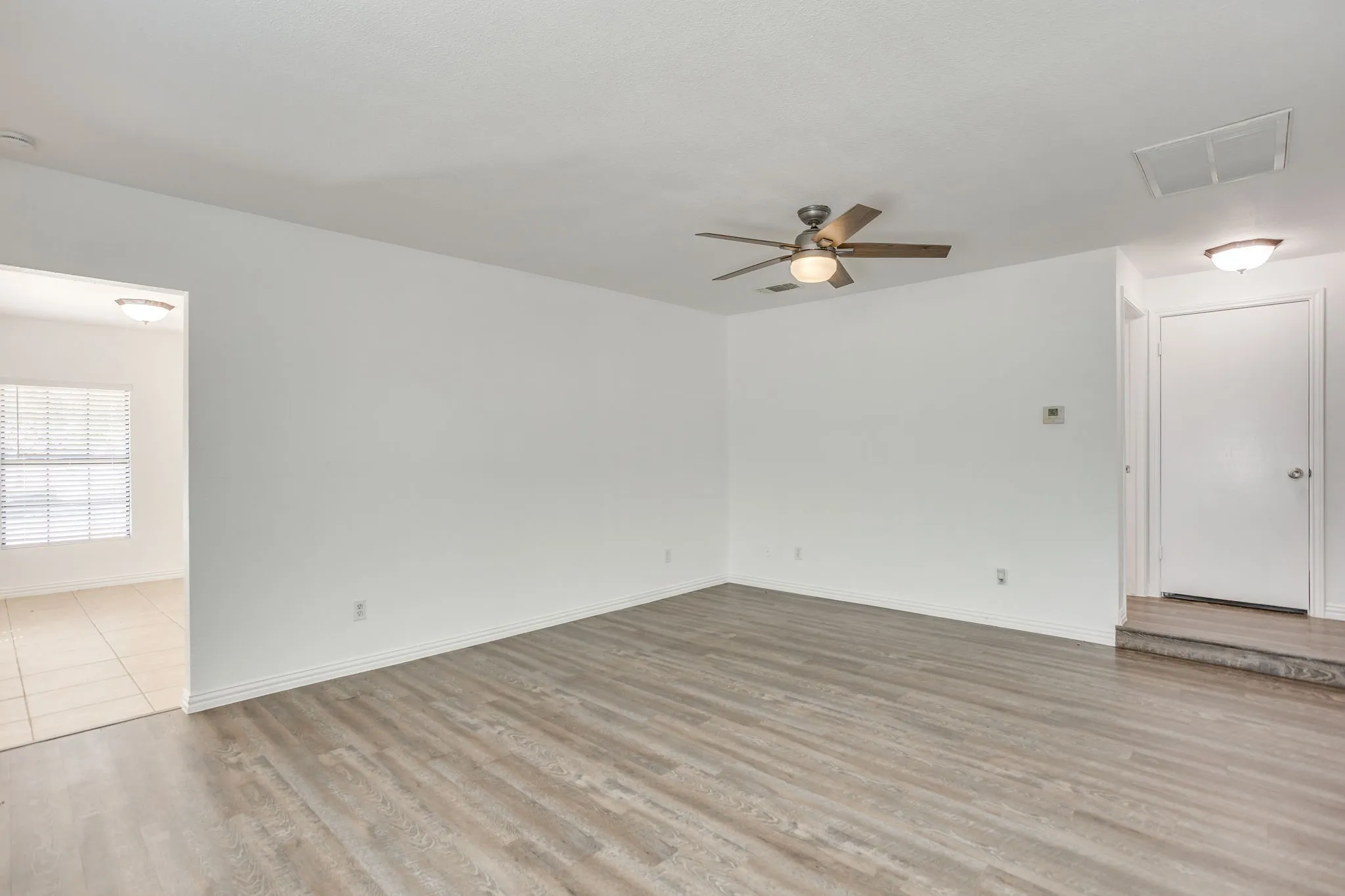 Bright interior with wood-finish flooring, a ceiling fan, and white painted walls