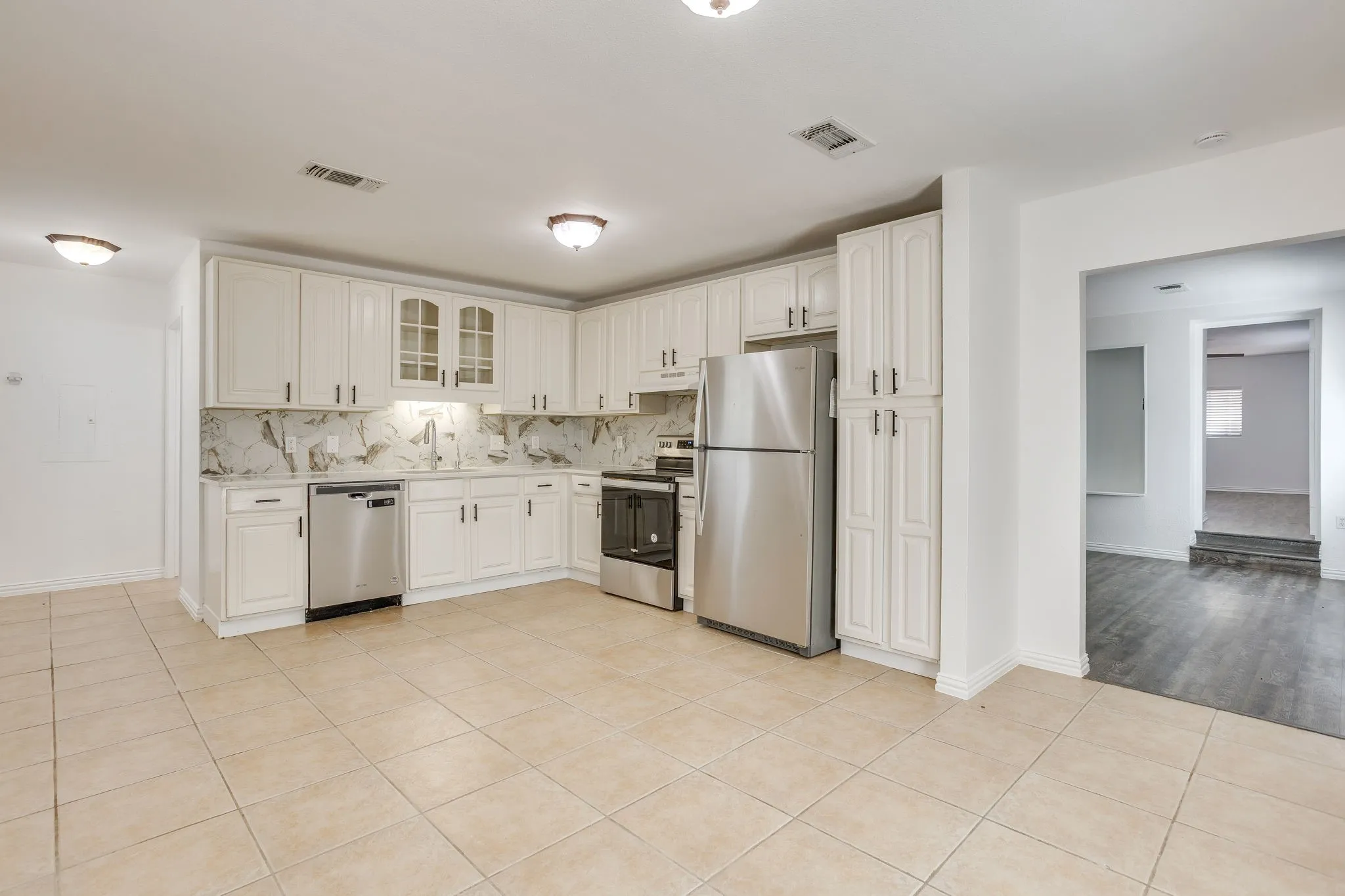 Kitchen featuring white cabinetry, stainless steel appliances, a tile backsplash, and light-toned tile flooring