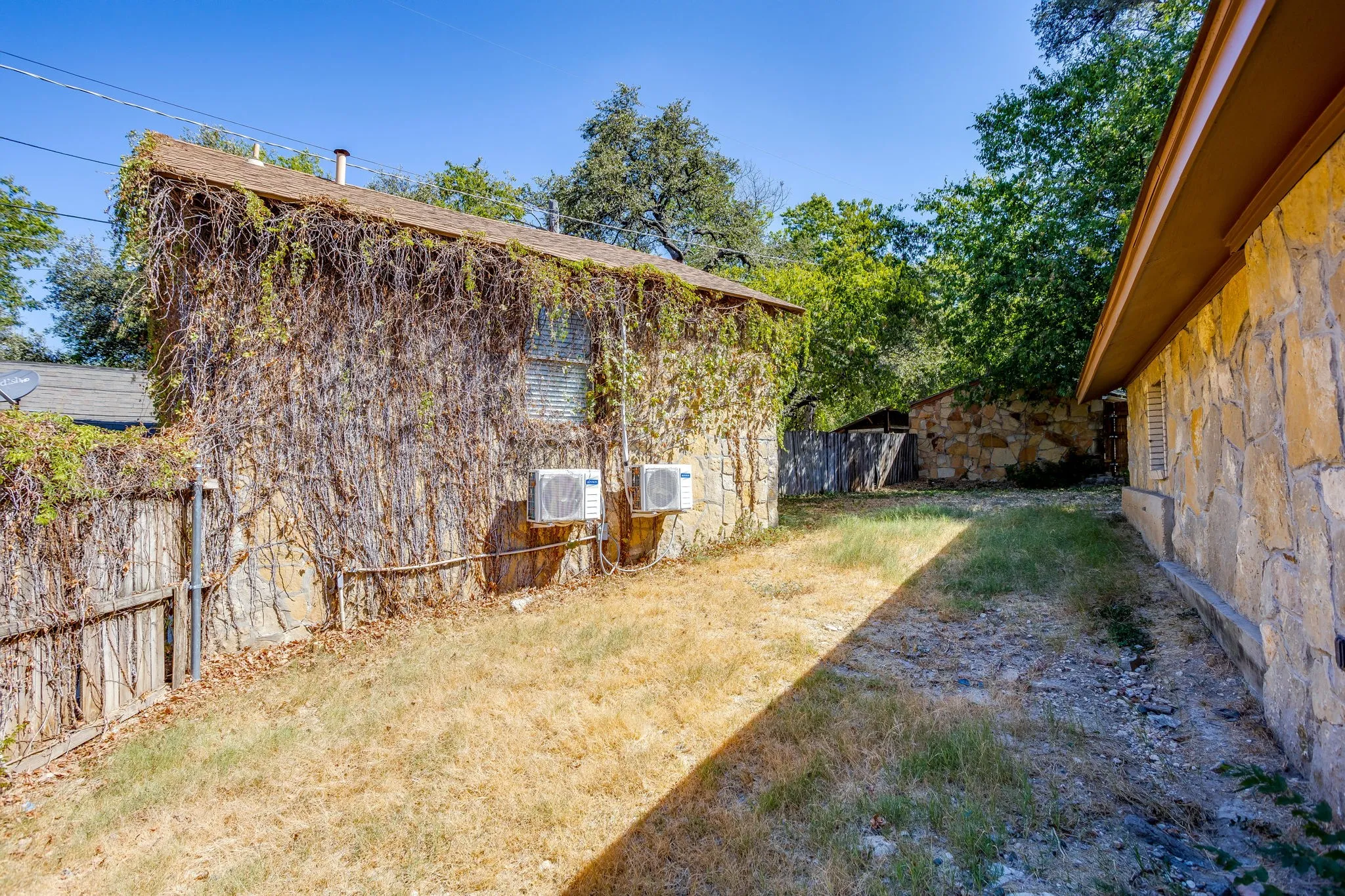 Stone exterior with a wood fence and mature trees