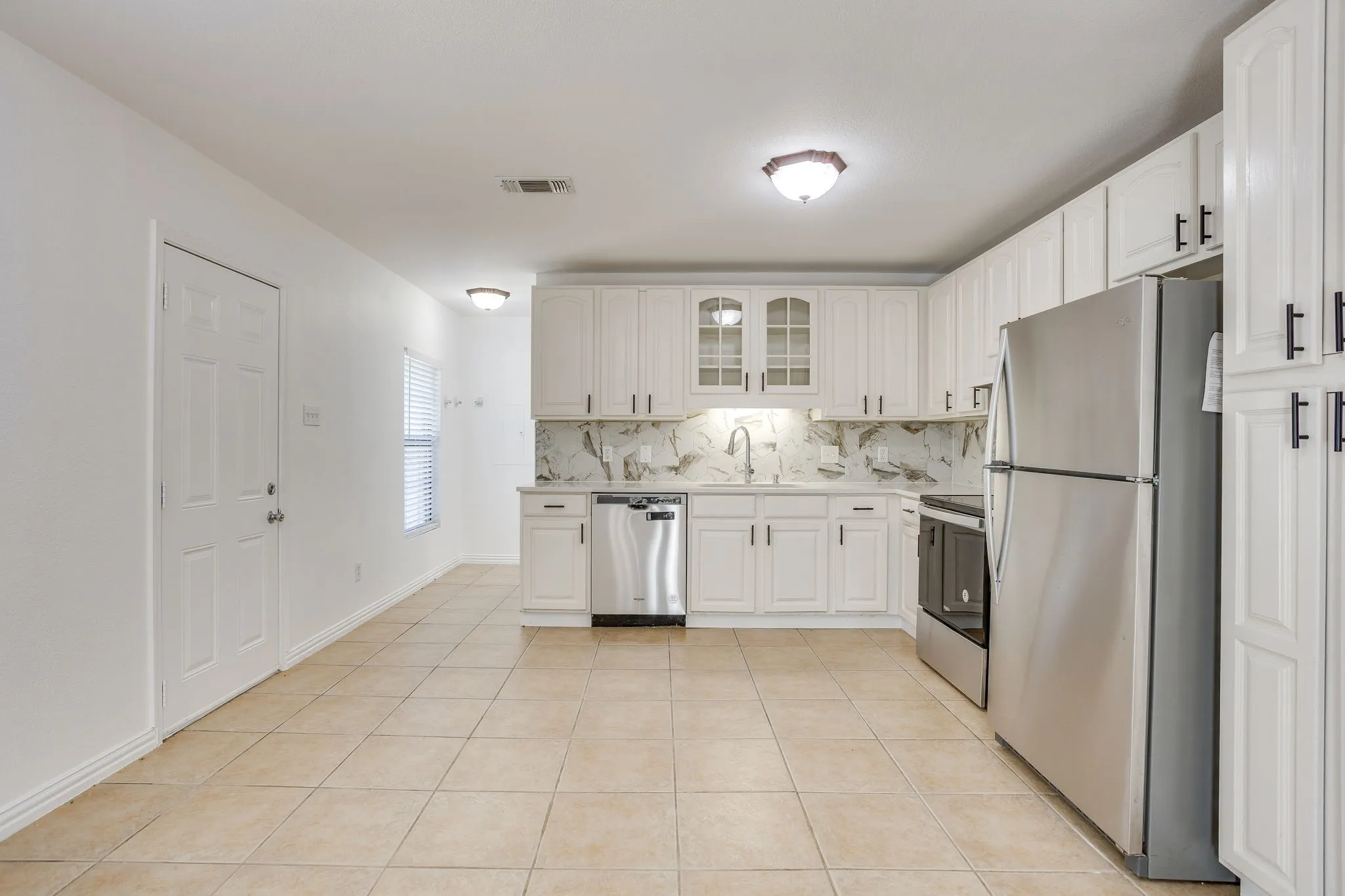 Kitchen featuring white cabinetry, stainless steel appliances, a tile backsplash, tile flooring, and recessed lighting