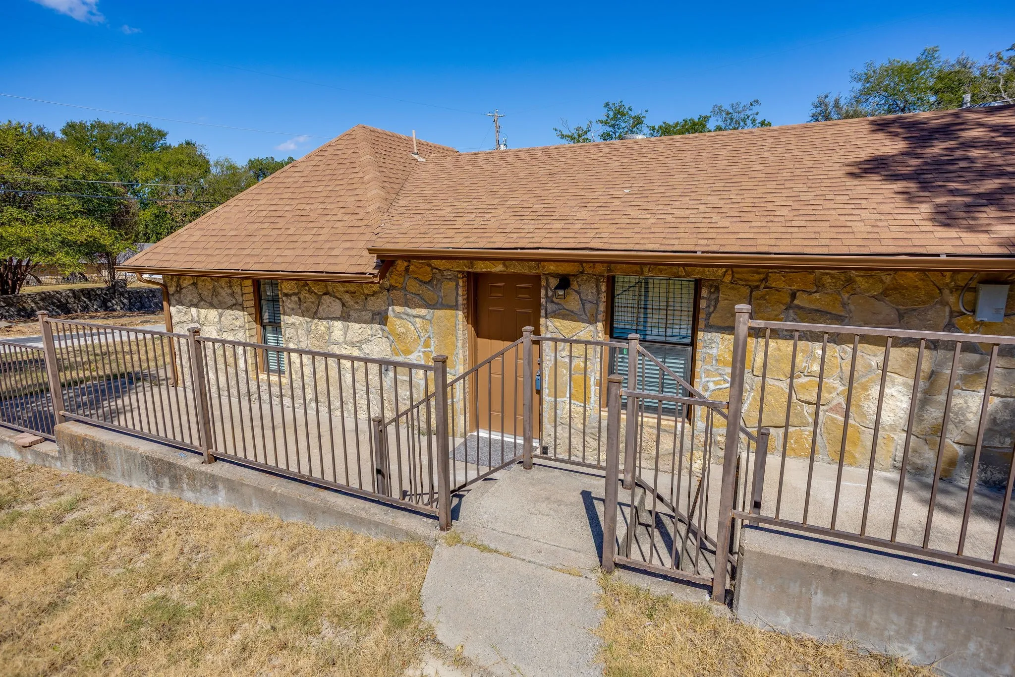 Stone exterior with a shingle roof and brown gutters